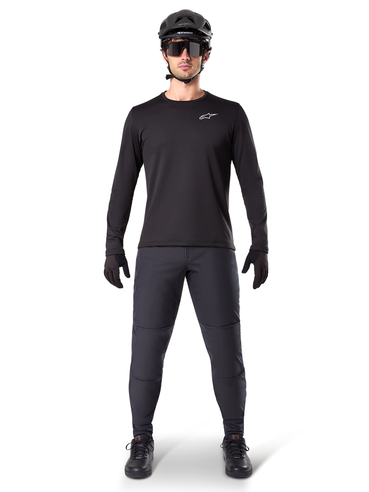 Alpinestars A-Dura Thermal Jersey, zwart mountainbike-jersey met lange mouwen, gedragen met een donkergrijze broek, zwarte handschoenen, zwarte helm en zonnebril, voorzien van een wit Alpinestars-logo op de borst, gecoördineerde outfit voor mountainbiken in koud weer