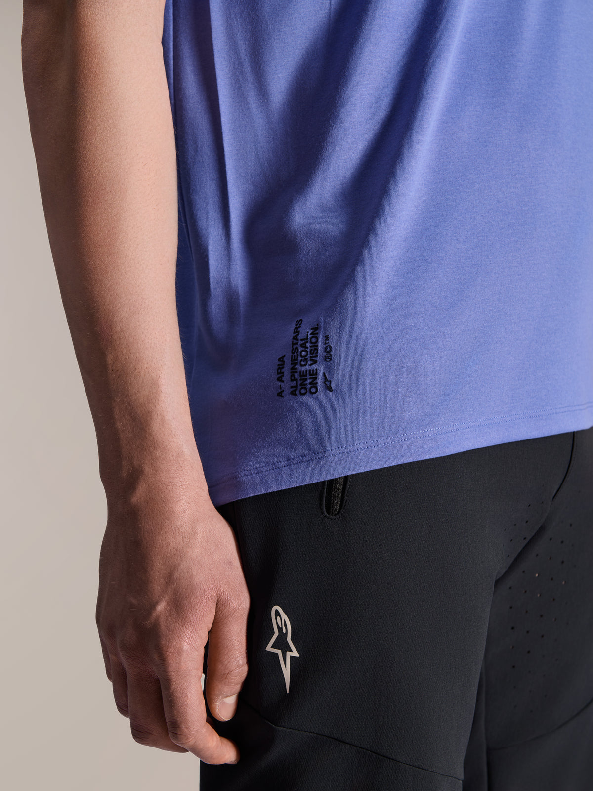 Alpinestars A-Aria Polartec Elite jersey met korte mouwen in Baja Blue, detail van de onderste zijzoom met zwarte 'One Goal. One Vision.' tekst en ASTARS-logobranding, gecombineerd met een zwarte mountainbike short.