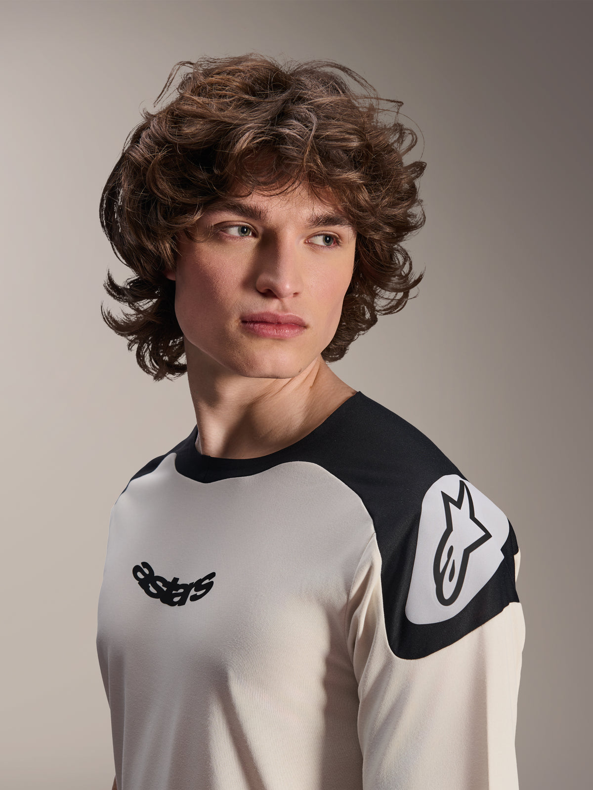 Alpinestars A-Aria Polartec Elite Jersey met korte mouwen, ecru met zwarte schouderpanelen, zwart Astars-logo op de borst en wit Astars-logo op de schouder, hoogwaardige mountainbikekleding gedragen door een model