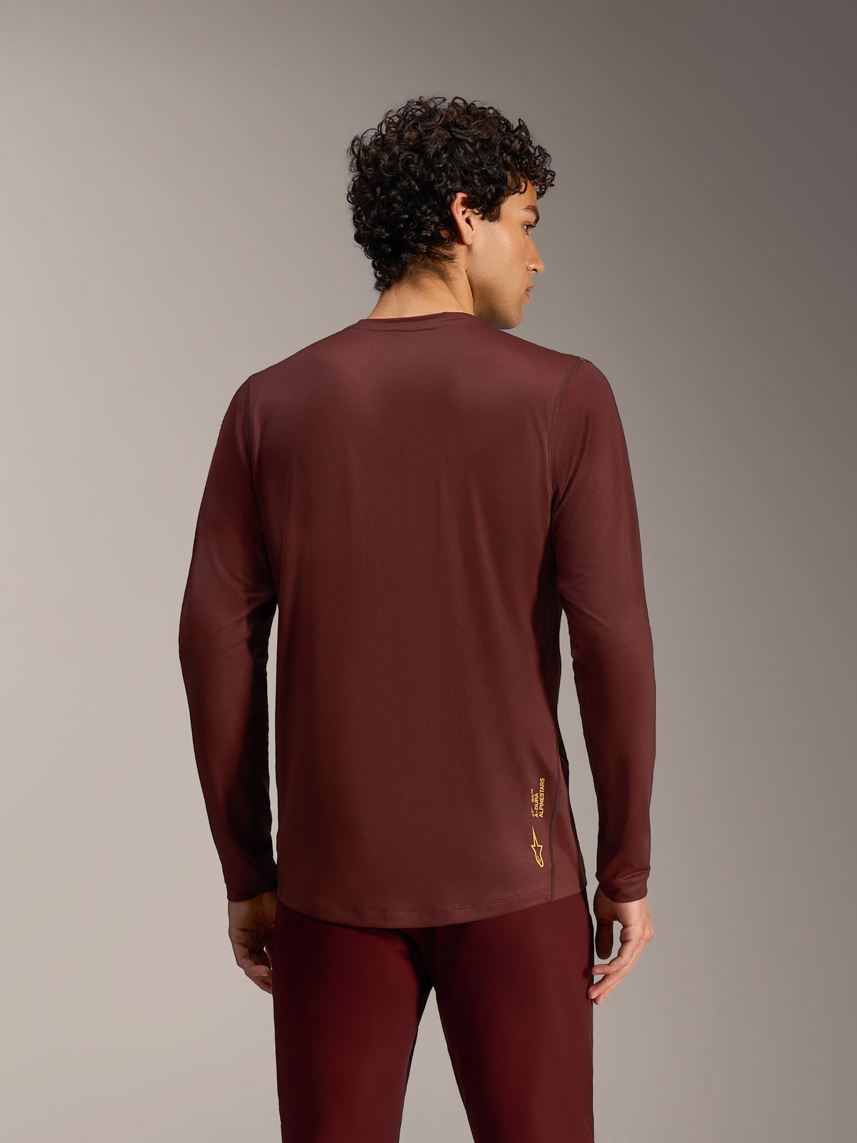 Alpinestars A-Dura Ride Trikot mit langen Ärmeln in Bordeaux, Rückansicht mit verlängertem Saum und Funktionsmaterial.
