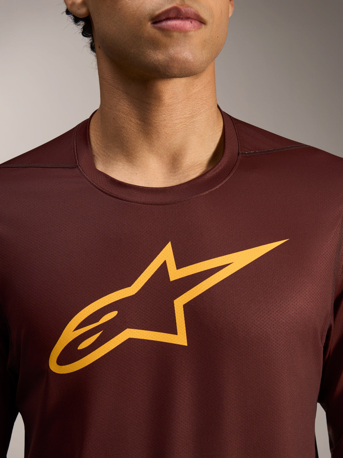 A-Dura Ride Langarmtrikot in Bordeaux mit gelber Astars-Logo-Grafik auf Performance-Jacquard-Gewebe.