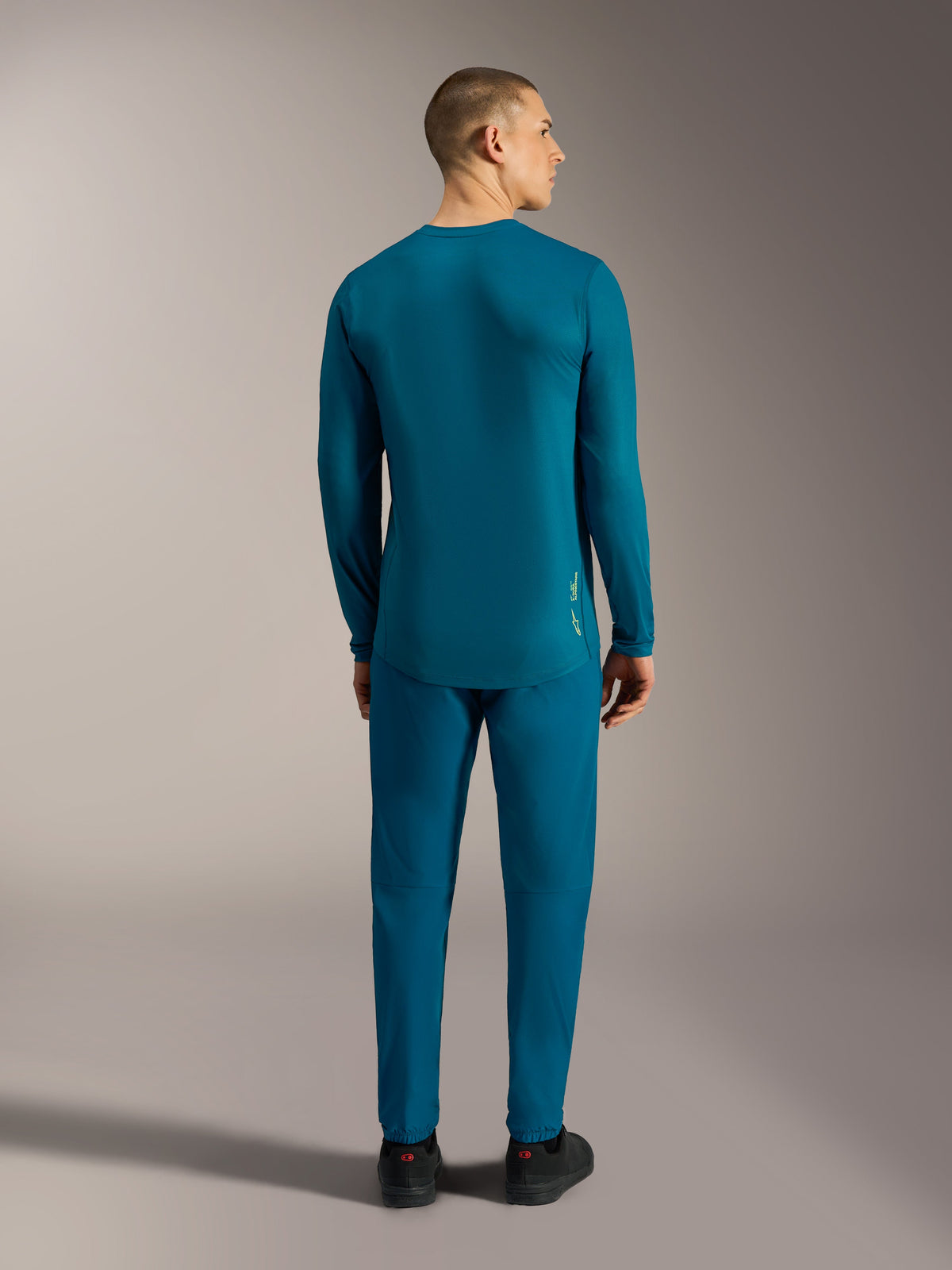 A-Dura Ride Long Sleeve Jersey in blue green, back view featuring a dropped tail hem for mountain bike performance.