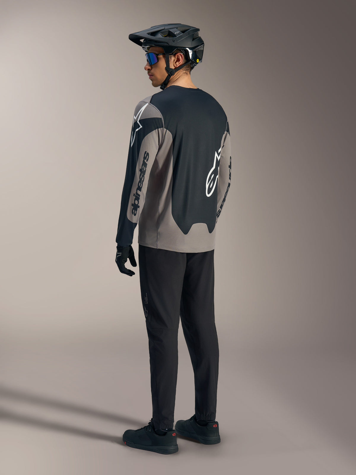 Maillot A-Dura Race à manches longues gris et noir Alpinestars, vu de dos dans une tenue de VTT complète.