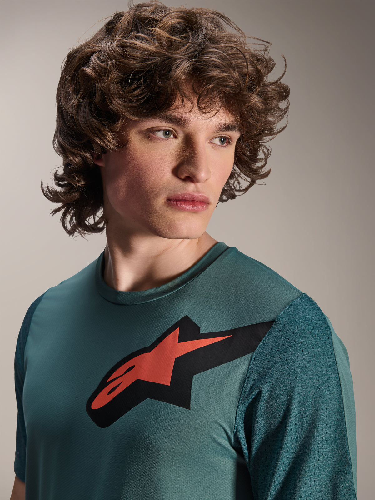 Alpinestars A-Dura Lipan Jersey, maillot de VTT à manches courtes, Silver Pine, avec un logo Astars rouge et noir sur la poitrine, manches en jacquard texturé, portrait en gros plan d'un mannequin portant une tenue de cyclisme haute performance