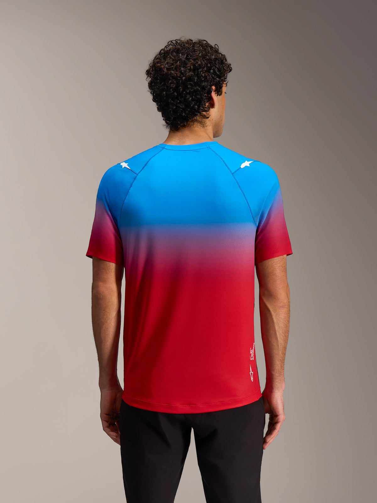 Alpinestars A-Dura ASTARS 2.0 fietsshirt, rood-blauw kleurverloop en sterlogo's op de schouders, achteraanzicht.
