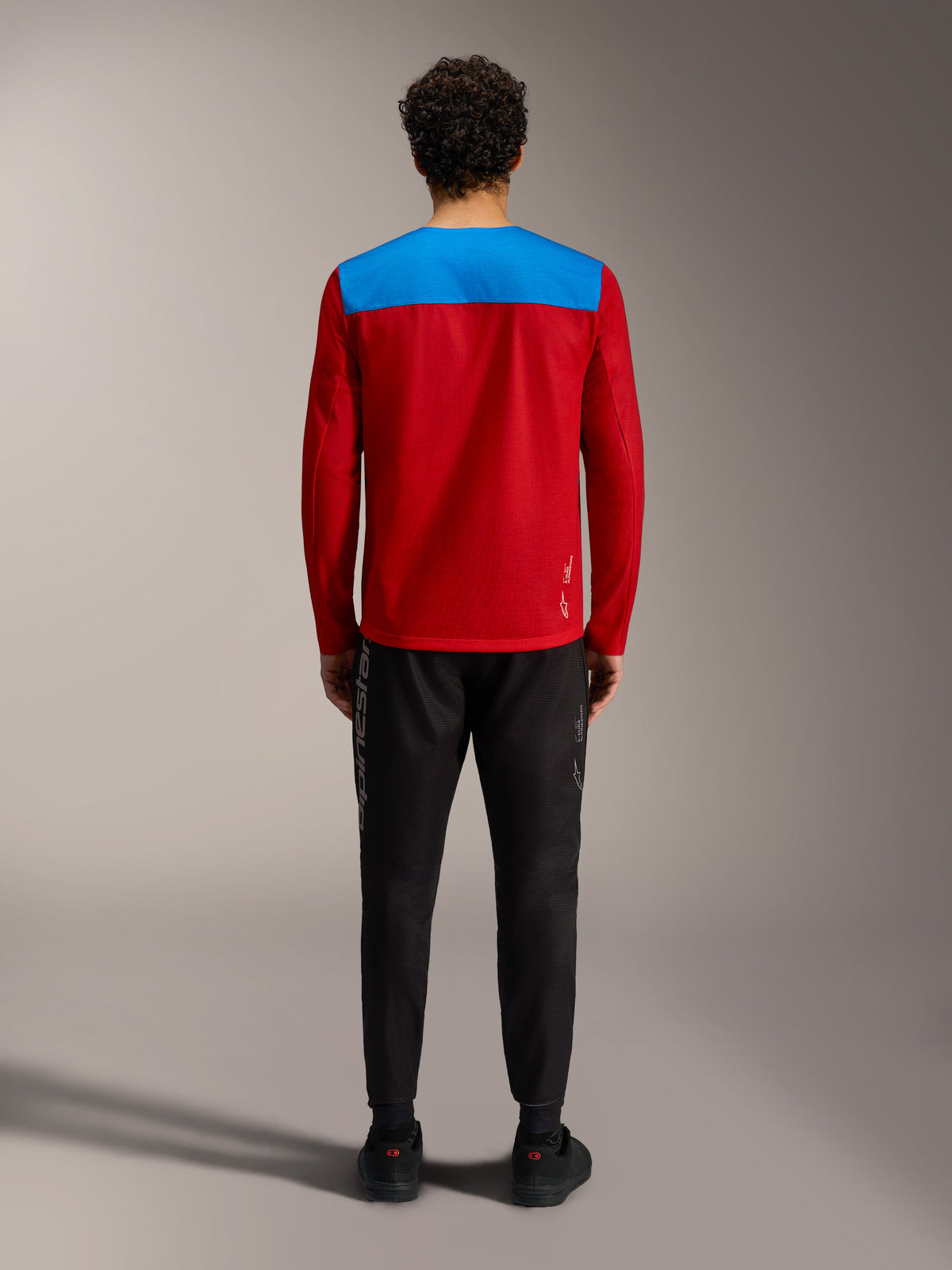 Alpinestars A-Dura Elite 2.0 MTB-trui, rood en blauw achteraanzicht, lange mouwen, met zwarte performance broek.
