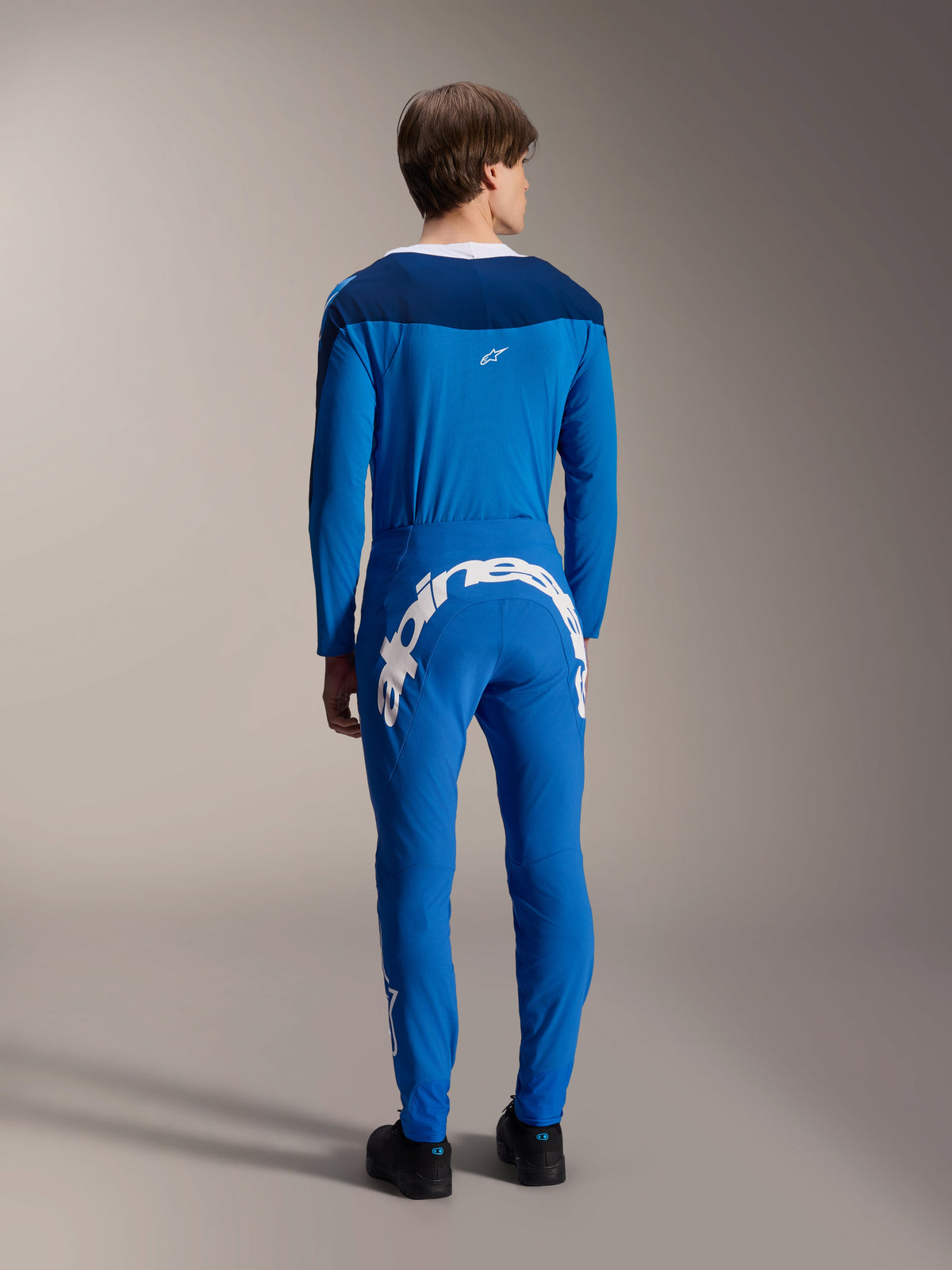 Alpinestars A-Supra Melt broek en bijpassende jersey met lange mouwen, blauw, achteraanzicht met focus op het grote witte Alpinestars-woordmerk op de achterpas, performance MTB-uitrusting met een flexibele atletische pasvorm