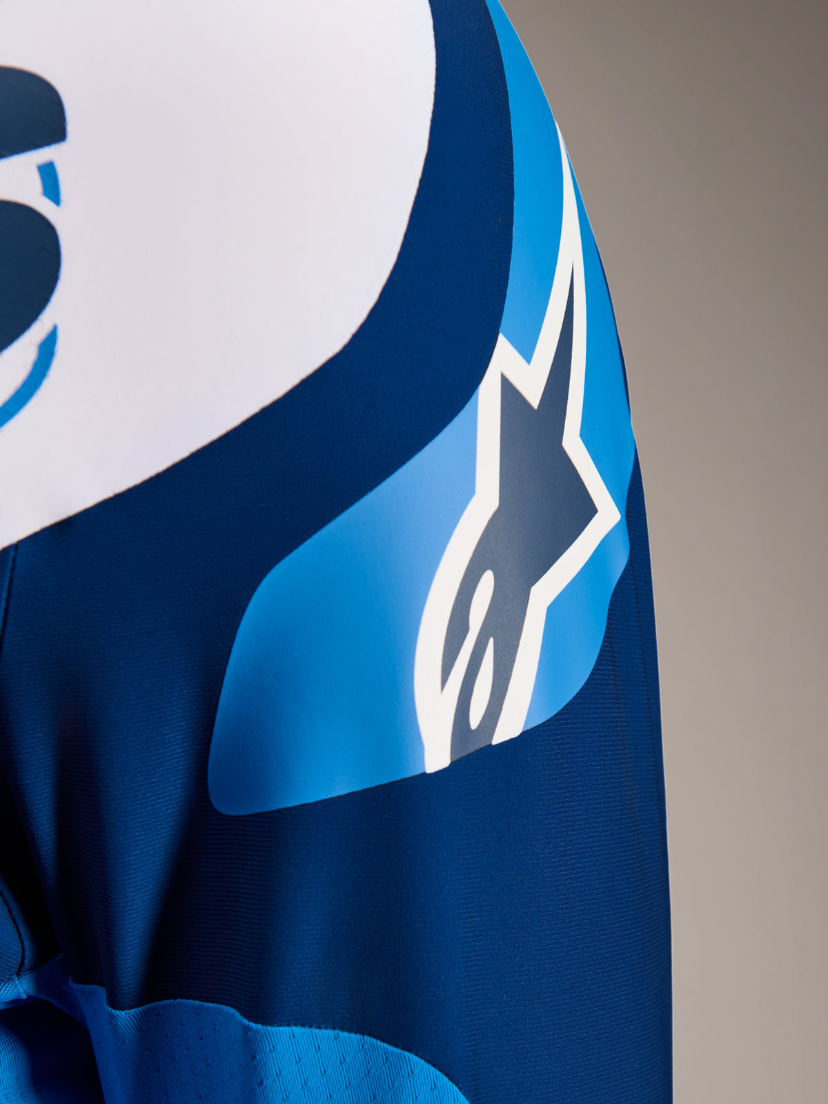 Alpinestars A-Supra Melt Jersey, Langarm-MTB-Trikot in Blau, Nahaufnahme des Ärmels mit ASTARS-Logo-Grafik und mikroperforiertem Gewebe zur Belüftung