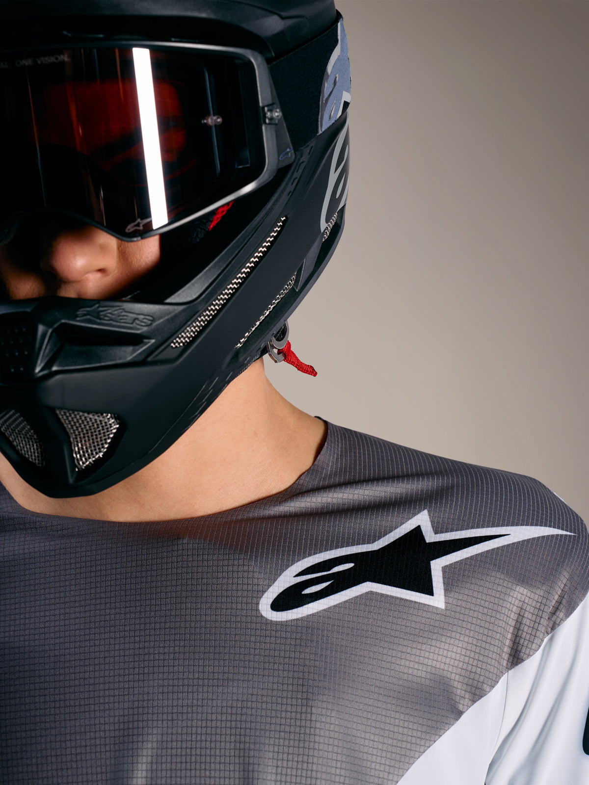 Alpinestars A-Supra Elite Trui in vervaagd grijs met wit logo, micro-geperforeerde stof en een zwarte MTB-helm.