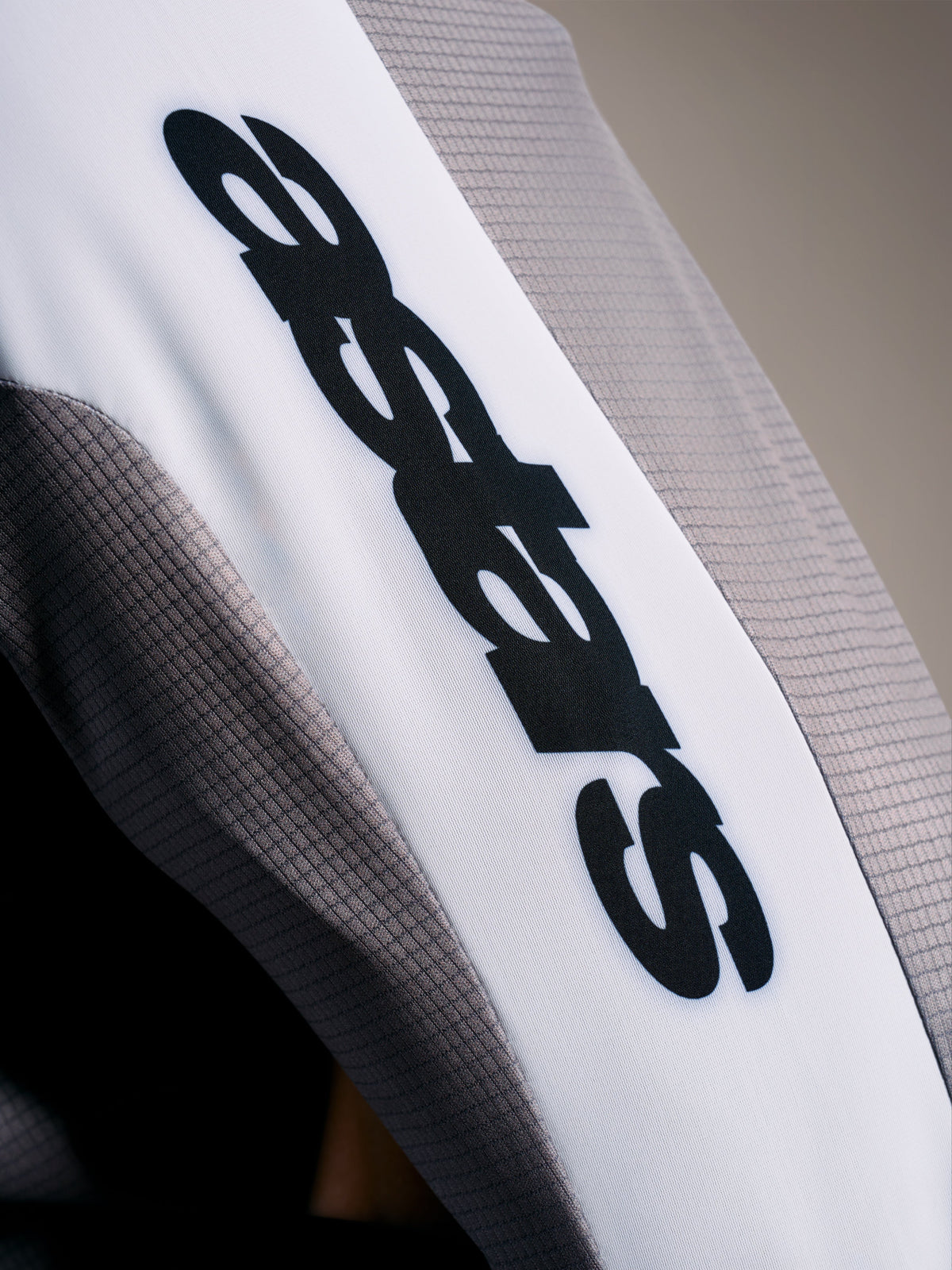A-Supra Elite Trui detail, Faded Gray micro-geperforeerde stof met zwart ASTARS-logo op een witte mouwband.