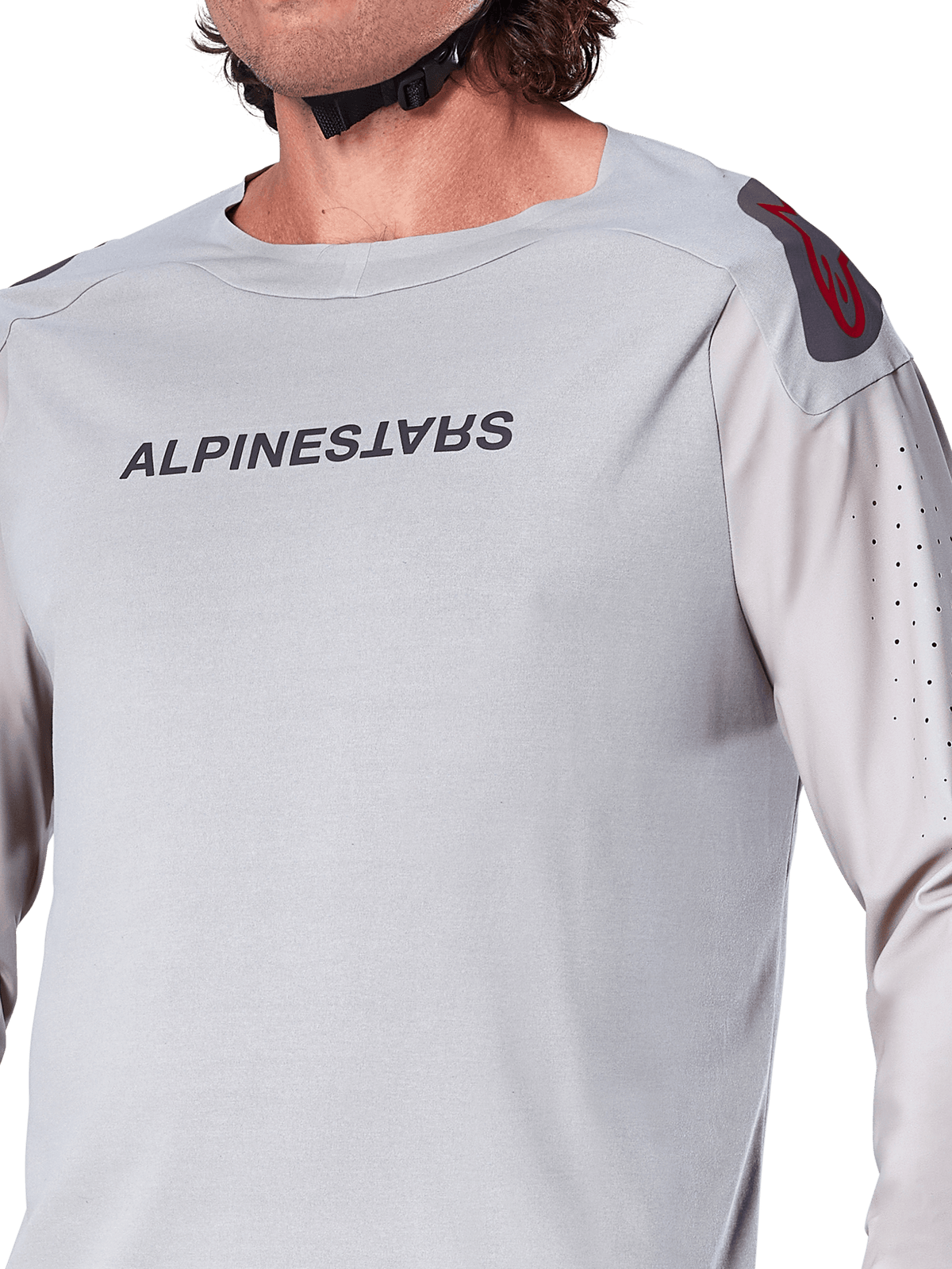 Nahaufnahme des Alpinestars A-Aria Polartec Switch Langarmtrikots in Hellgrau, mit Alpinestars-Branding auf der Brust, rotem Schulterlogo und laserperforierten Ärmeln für optimale Luftzirkulation, hochwertige Mountainbike-Ausrüstung.