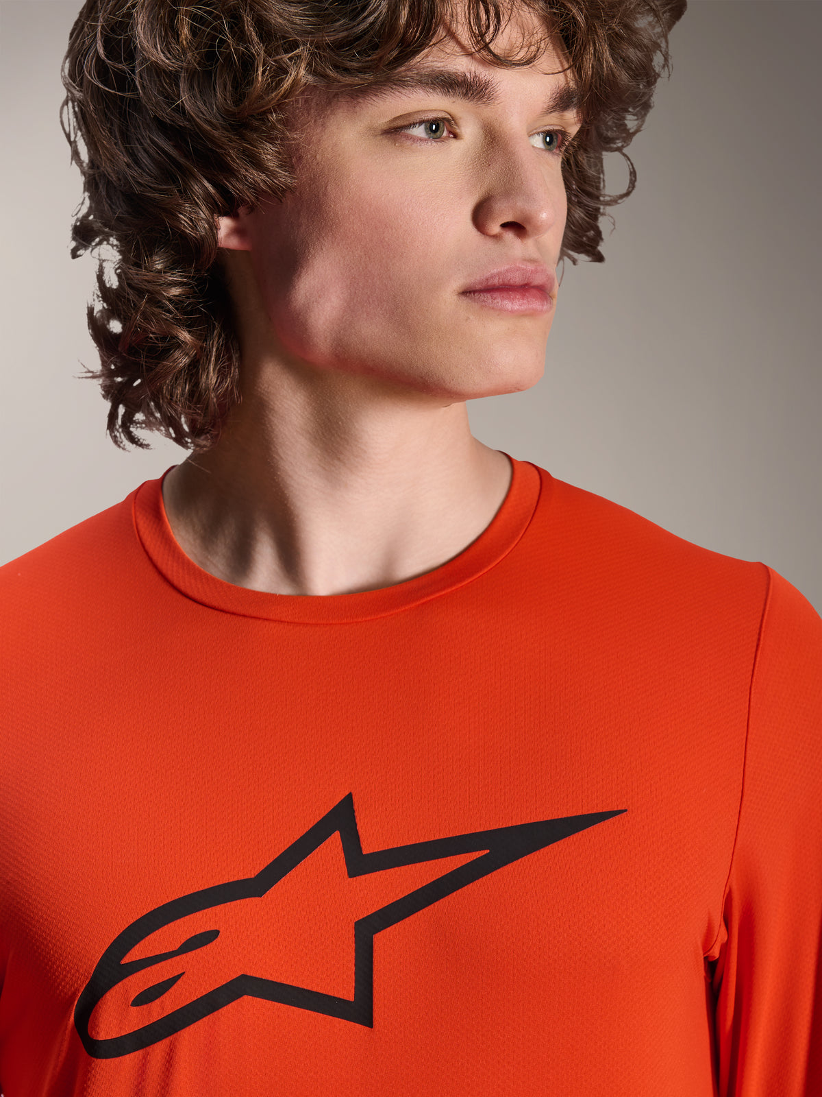 Alpinestars A-Dura Insert Astar Jersey, Long Sleeve MTB Jersey, Spicy Orange, featuring black Alpinestars Astar logo on the chest, close-up view on a male model