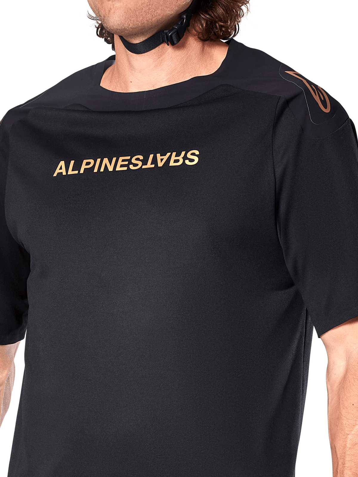 Maillot Alpinestars A-Aria Polartec Switch, maillot de VTT à manches courtes, noir, lettrage Alpinestars doré sur la poitrine et logo sur l'épaule, gros plan sur le haut du torse mettant en avant le tissu technique et la coupe performance