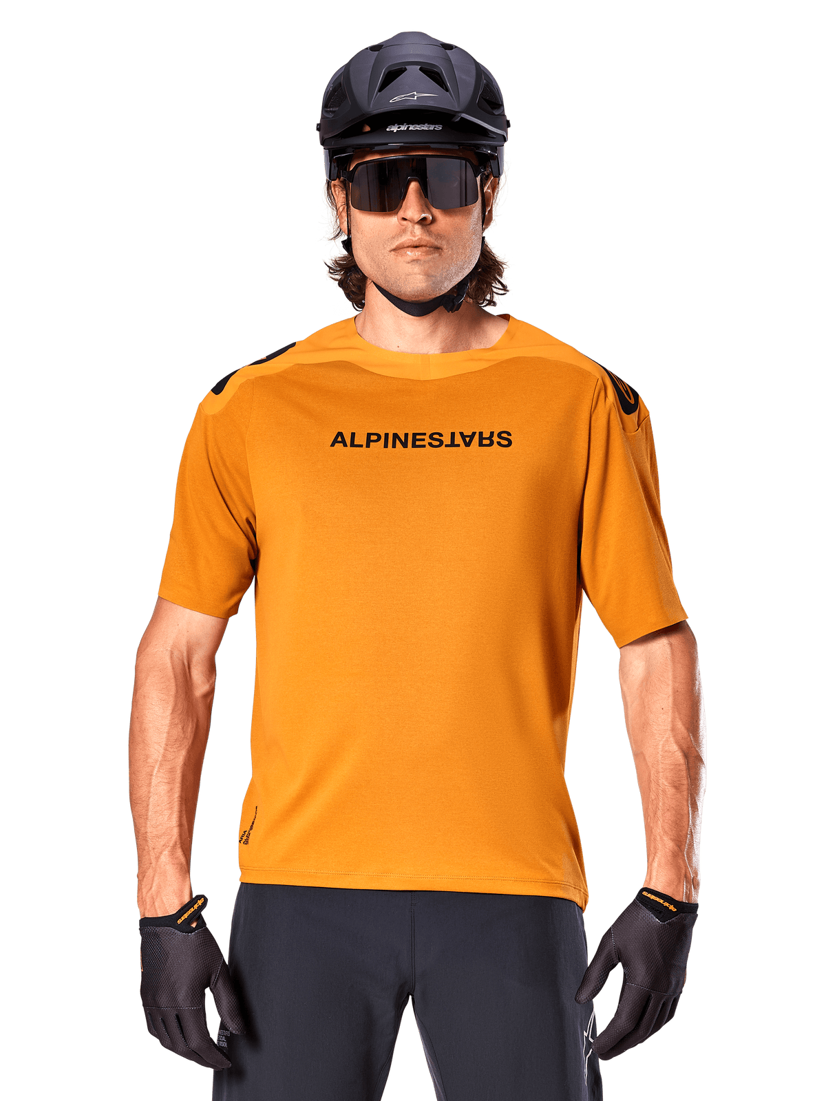 Maillot à manches courtes Alpinestars A-Aria Polartec Switch, or foncé, cycliste de VTT portant un casque noir et des lunettes de soleil, vêtement de cyclisme haute performance pour les sentiers de VTT