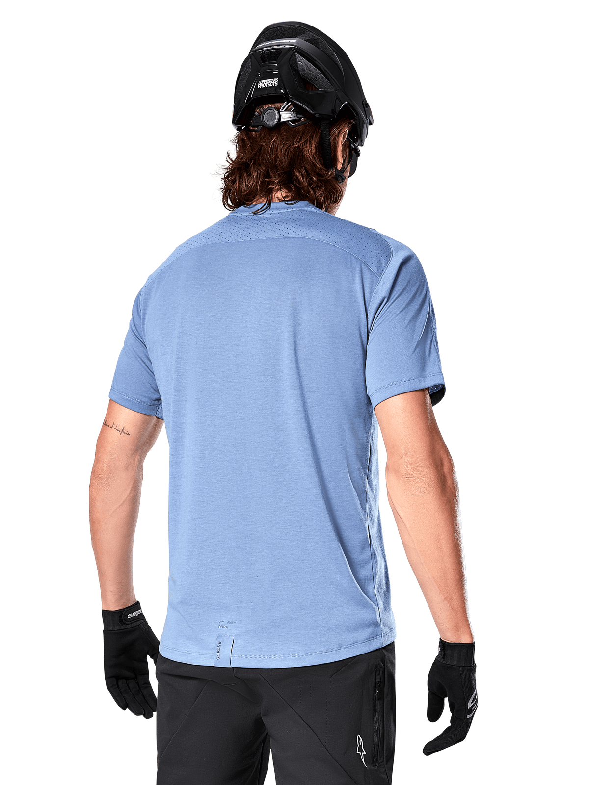 Alpinestars A-Dura Dri Astar jersey met korte mouwen, MTB-jersey, Infinity Blue, achteraanzicht met mesh ventilatiepanelen op de schouders en een langere achterzijde, gedragen met een zwarte MTB-helm en handschoenen, technische fietskleding