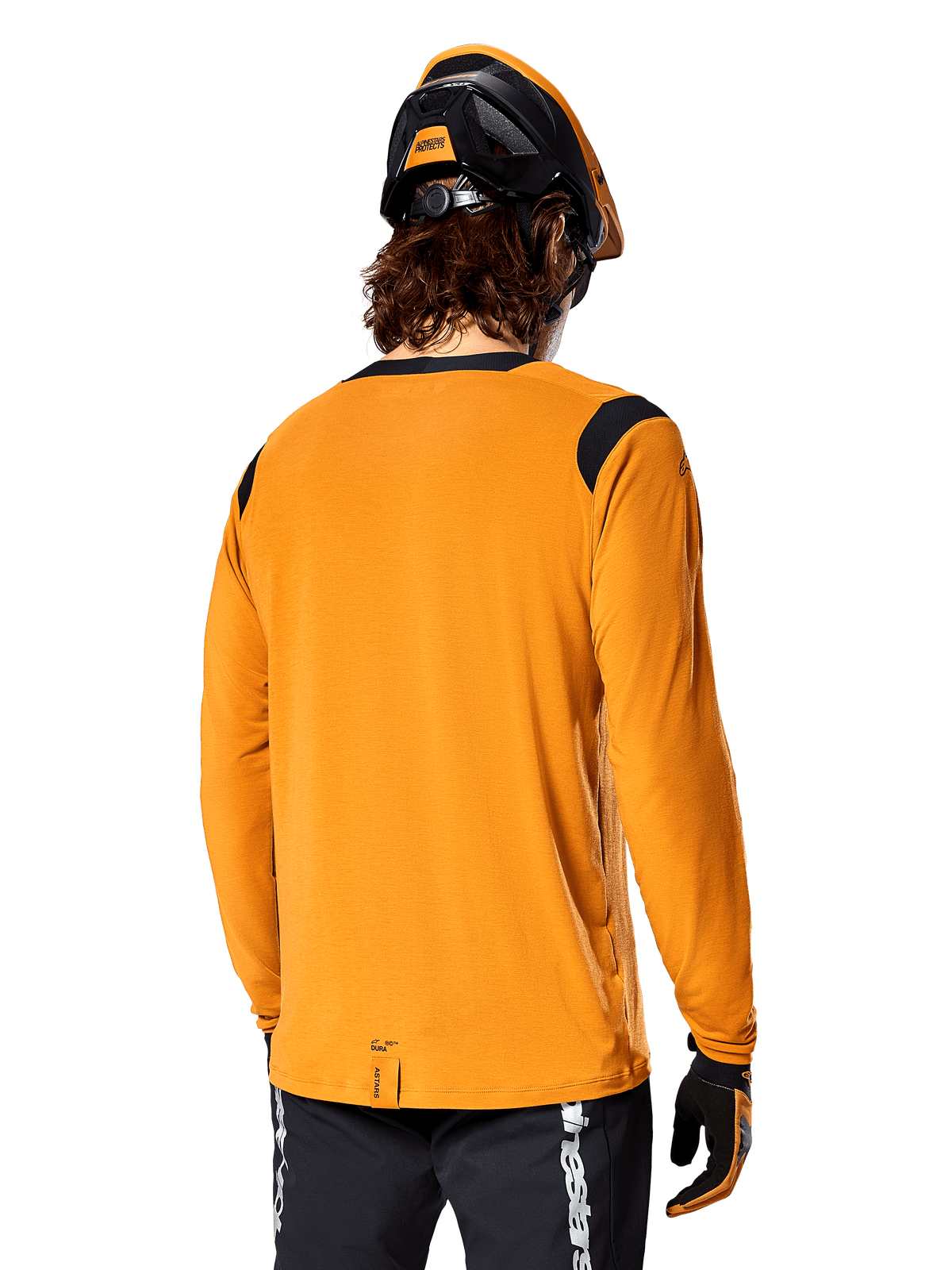 Maillot à manches longues Alpinestars A-Dura Dri Wool en Dark Gold, vue arrière d'un cycliste portant un casque de VTT et des gants, doté de panneaux en maille noire sur les épaules et d'un pan arrière plus long, vêtement technique de cyclisme pour le trail