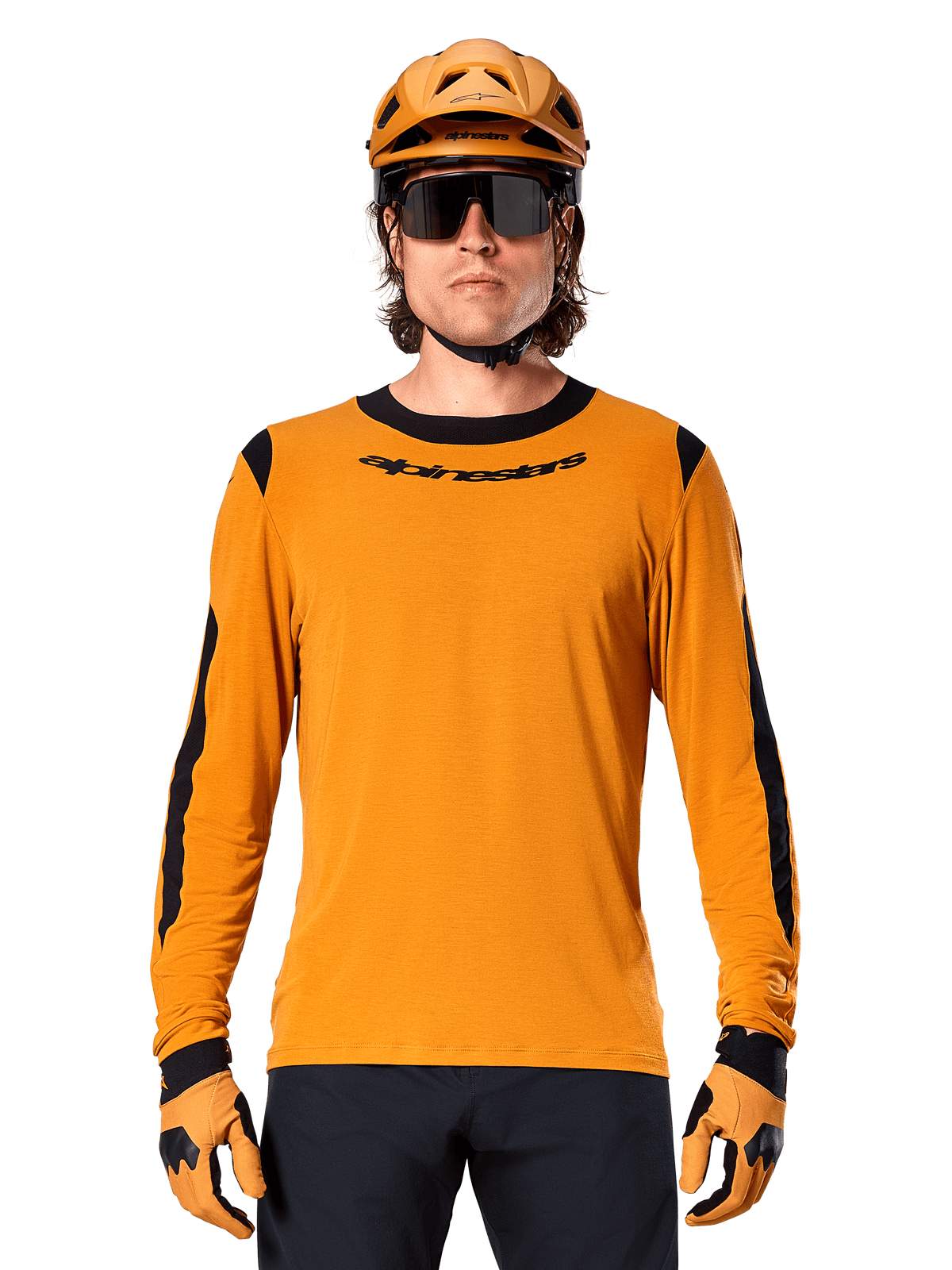 Maillot à manches longues Alpinestars A-Dura Dri Wool en Dark Gold, porté par un modèle masculin avec casque de VTT et gants dorés assortis, empiècements en maille noire sur les épaules et les manches, logo Alpinestars noir sur la poitrine, lunettes de soleil et pantalon sombres, tenue technique de VTT