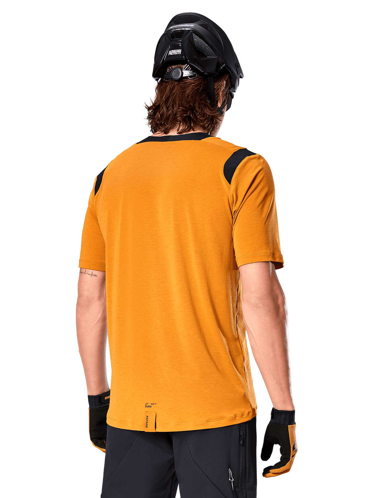 Maillot à manches courtes Alpinestars A-Dura Dri Wool, Or foncé, vue arrière d'un homme portant le maillot avec des panneaux en maille noire sur les épaules, associé à un casque de VTT et des gants noirs, équipement de VTT à coupe régulière.