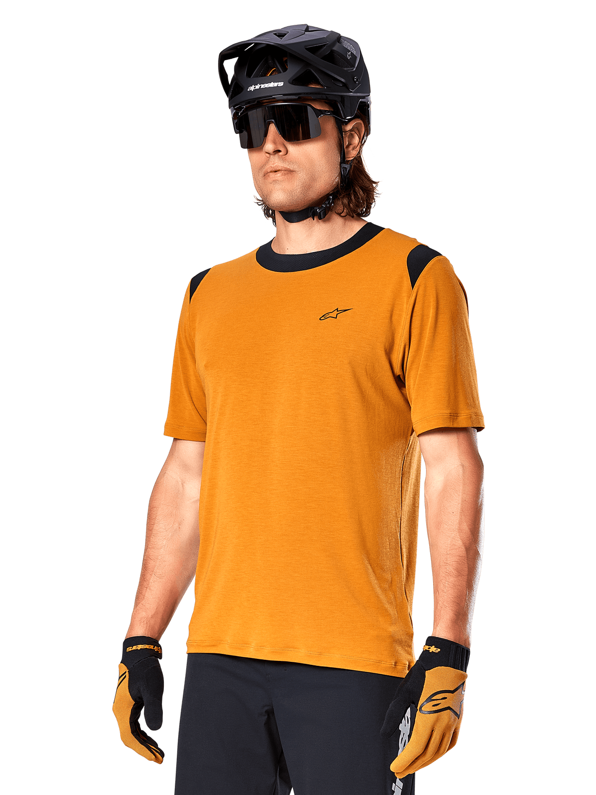 Maillot Alpinestars A-Dura Dri Wool à manches courtes, maillot de cyclisme VTT, Or foncé avec accents noirs, maillot technique à manches courtes en mélange de laine avec empiècements noirs aux épaules, porté avec un casque de VTT noir et des gants assortis