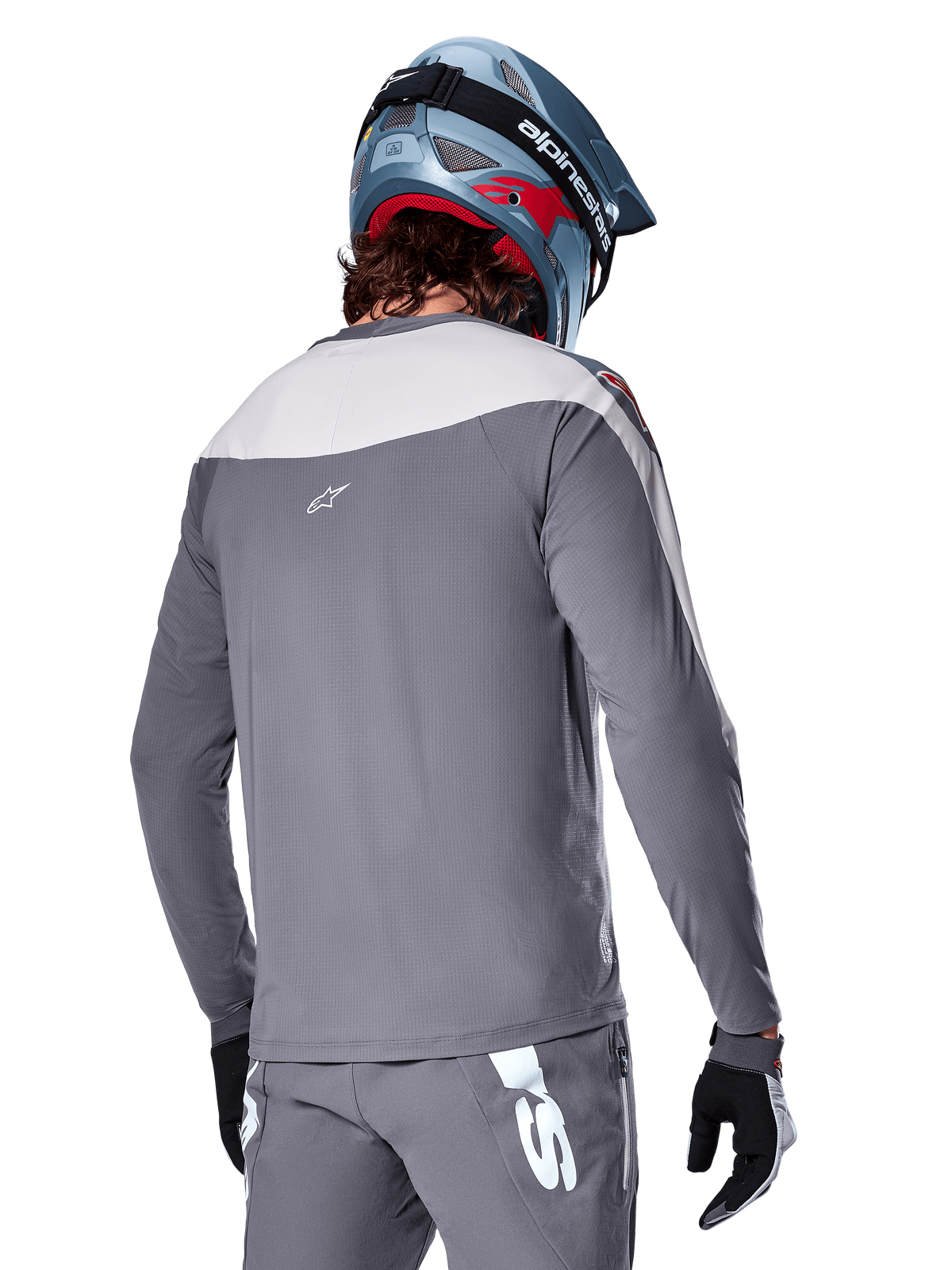 Maillot Alpinestars A-Supra Race, maillot de VTT à manches longues gris foncé et gris clair, vue arrière montrant la coupe performance et le logo Astar, porté avec un pantalon gris assorti et un casque de VTT bleu, conçu pour la pratique du VTT tout-terrain