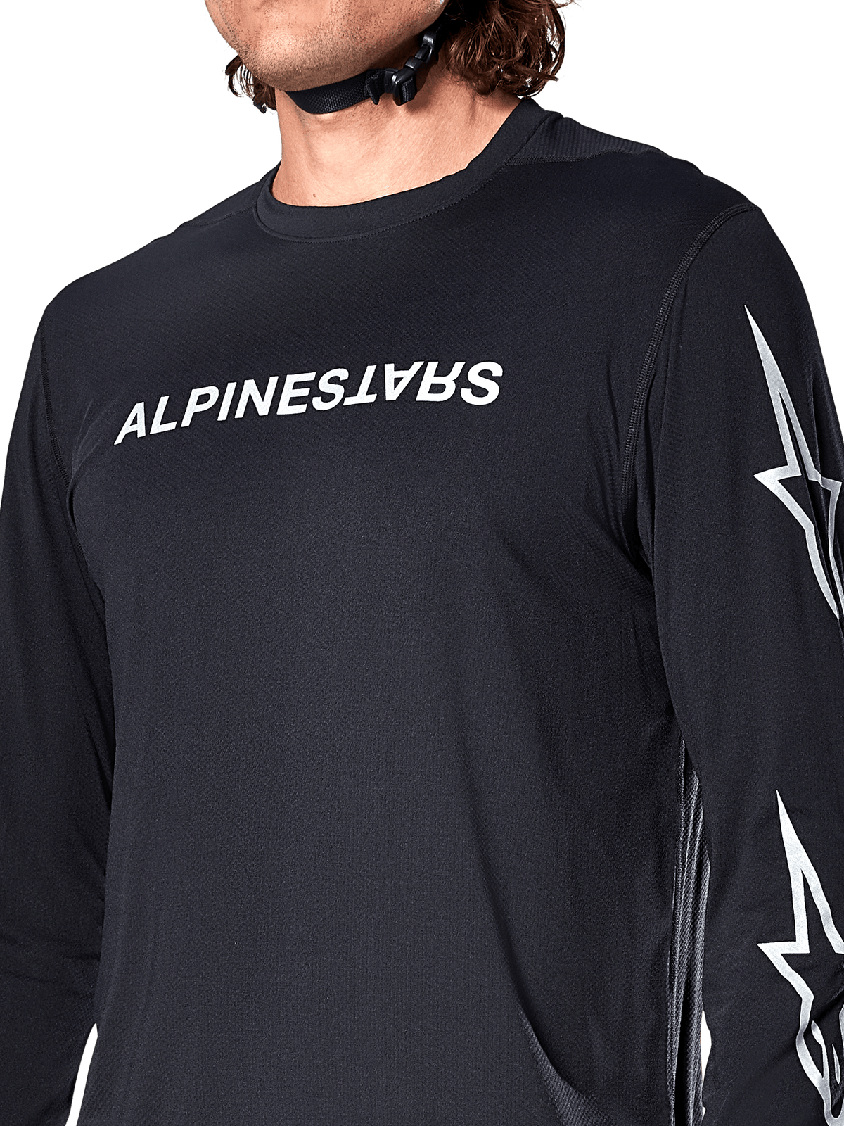 Alpinestars A-Dura Switch Jersey met lange mouwen, zwart, voorzien van wit Alpinestars-woordmerk op de borst en sterlogo's op de mouw, gedragen door een rijder met zichtbaar helmbandje, technische mountainbikekleding.
