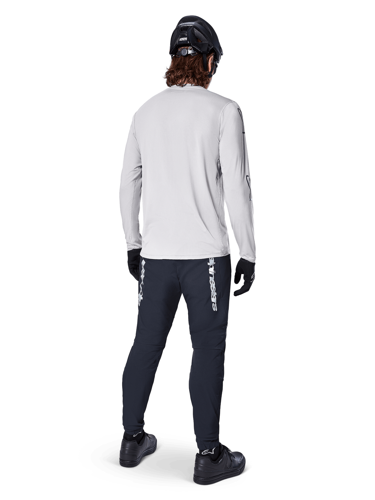 Alpinestars A-Dura Switch Long Sleeve Jersey, Light Gray, rear view on a rider wearing black cycling pants, helmet, and gloves, high-performance mountain bike gear with a longer drop tail.