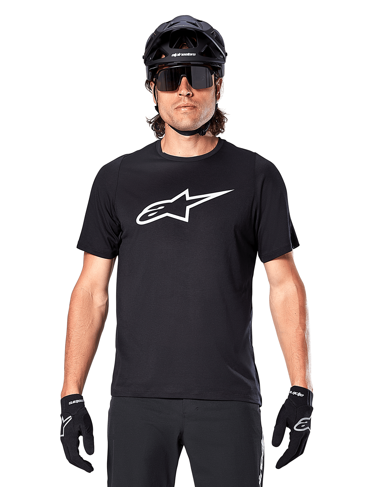 Alpinestars A-Dura Dri Oscar Kurzarmtrikot, Schwarz Reflektierend, getragen mit schwarzem MTB-Helm, Sonnenbrille und Handschuhen, mit markantem weißem Logo auf der Brust, Performance-Ausrüstung für Mountainbiking