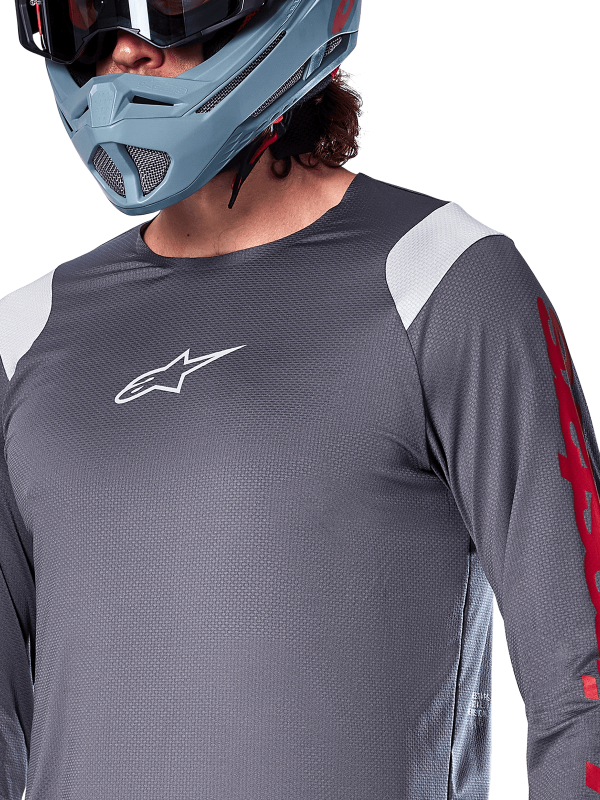 Alpinestars A-Supra Astar Long Sleeve Jersey, Dark Gray with white shoulder panels and red sleeve graphics, worn with a light blue-gray full-face helmet, performance mountain bike apparel