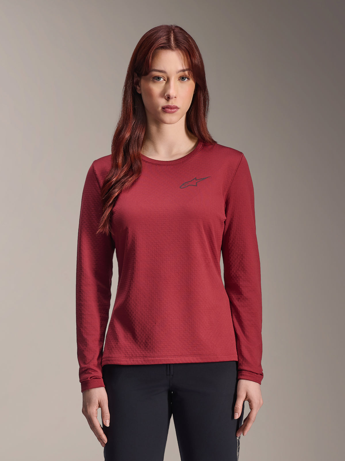 Alpinestars Stella A-Dura Thermal Jersey, MTB-fietsshirt met lange mouwen voor dames, bordeauxrood, gestructureerde thermische stof, ronde hals met een klein zwart Alpinestars-logo op de borst, gedragen door een model.