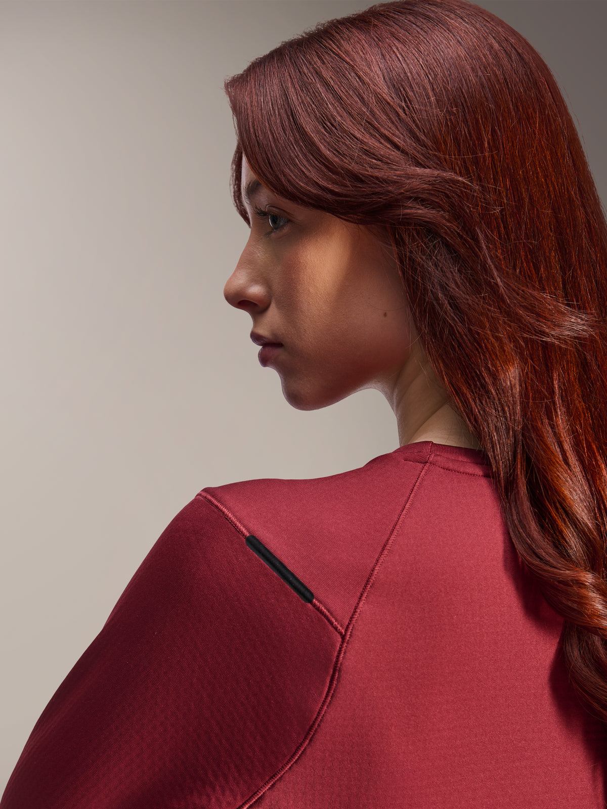 Vrouw in Alpinestars Stella A-Dura Thermal Jersey, bordeauxrode MTB-jersey met lange mouwen, close-up zijaanzicht gericht op details van de schoudernaad en de materiaaltextuur, lifestyle fietskleding
