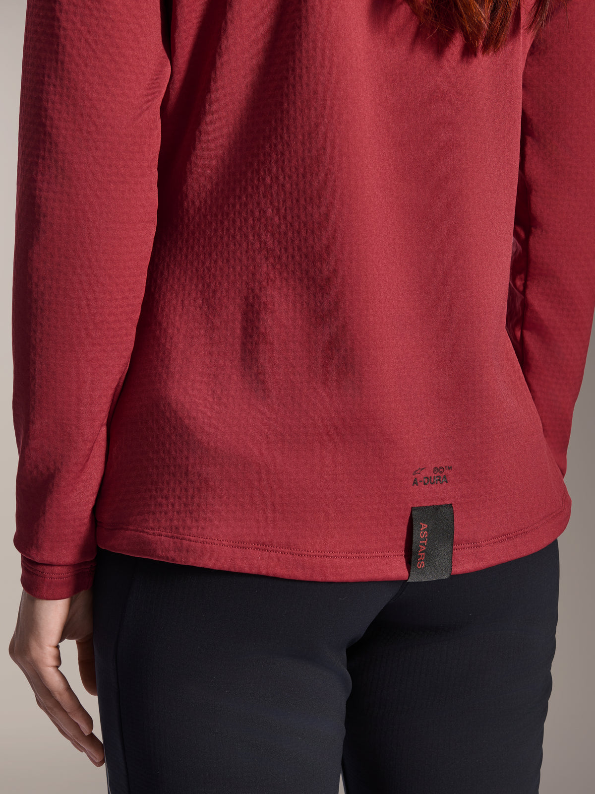 Alpinestars Stella A-Dura Thermal Jersey voor dames, Burgundy, close-up van de achterzoom met A-Dura-branding en geweven ASTARS-label, getextureerde geïsoleerde fleecestof, mountainbikekleding voor dames
