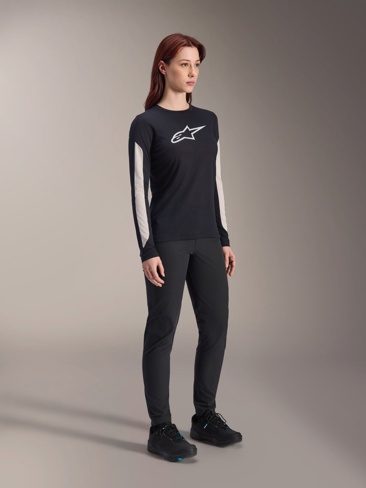 Alpinestars Stella A-Dura Dri Astar Langarmtrikot für Damen, Schwarz, mit weißen Mesh-Einsätzen an den Ärmeln und weißem Astar-Logo, getragen mit schwarzer Hose und Schuhen, technische Radsport-Funktionsbekleidung für Mountainbiking