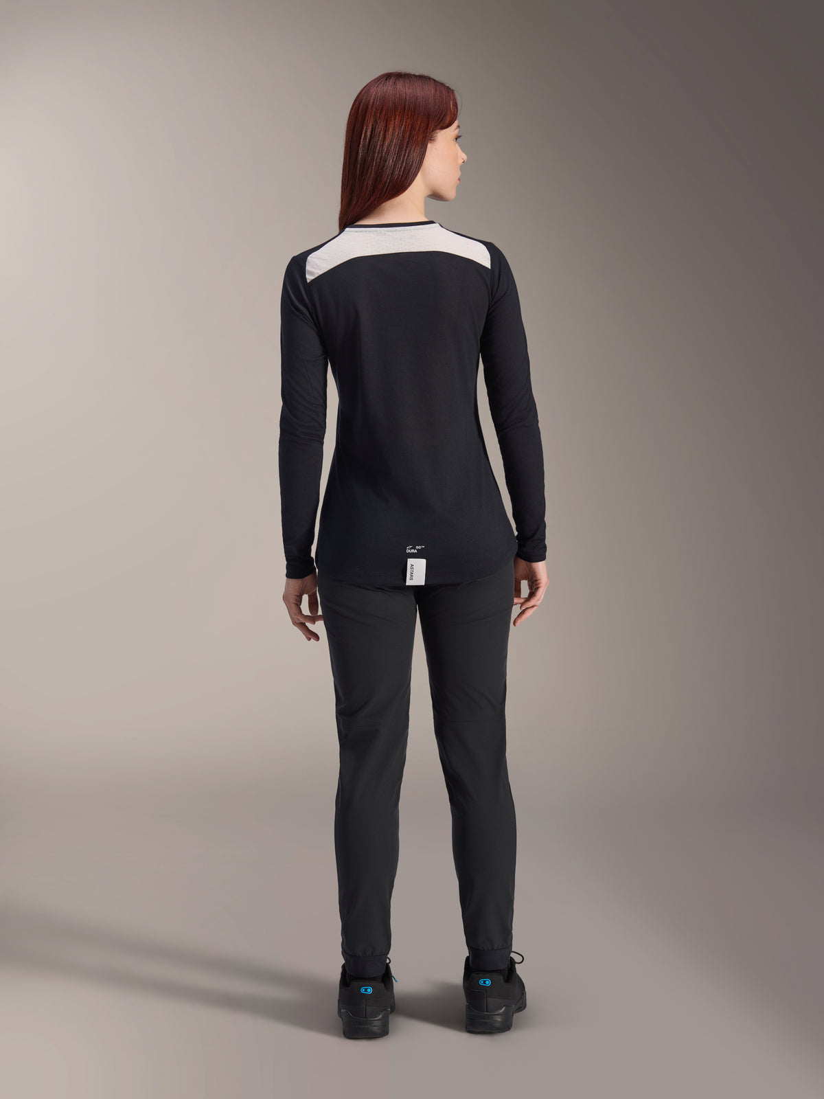 Alpinestars Stella A-Dura Damen-Hose und Stella A-Dura Elite Trikot, MTB-Fahrradbekleidung, Schwarz mit weißem Schultereinsatz, Rückansicht, technische Outdoor-Bekleidung für Mountainbiking, kombiniert mit schwarzen Schuhen