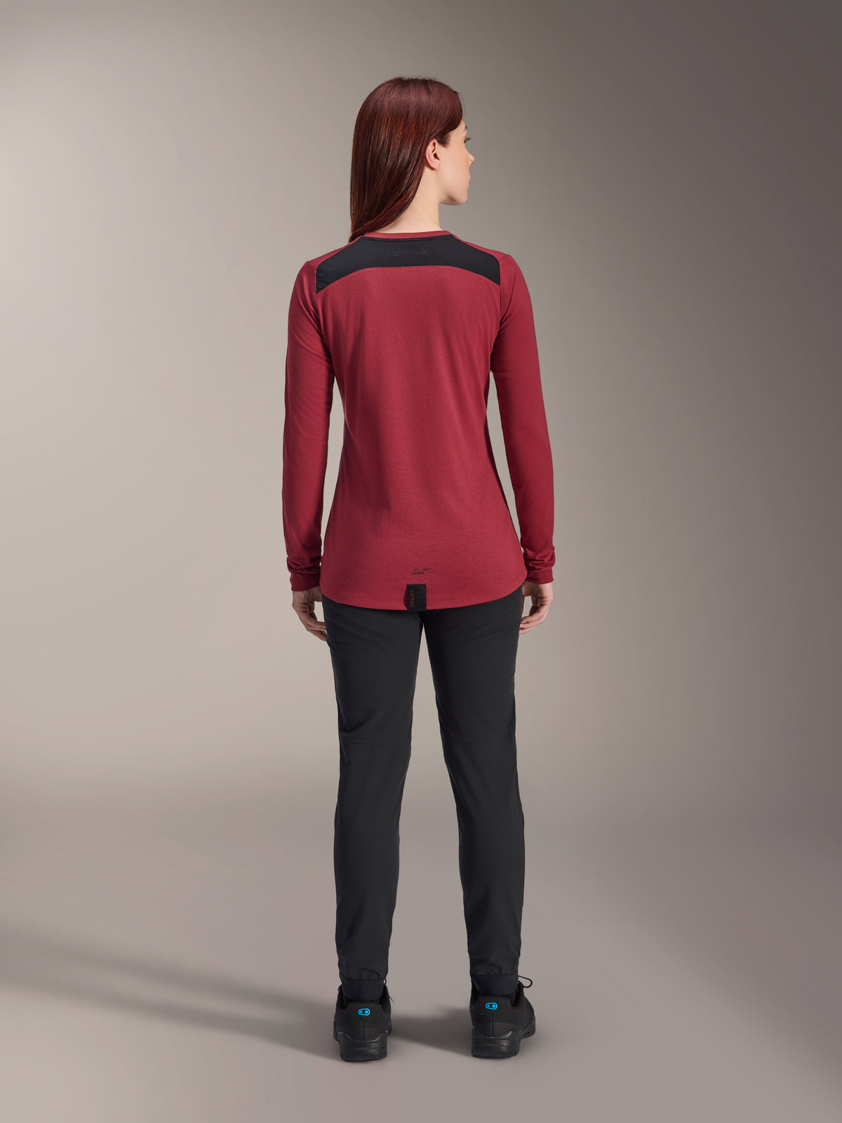 Alpinestars Women Stella A-Dura Dri Astar Long Sleeve Jersey, Burgundy Red with black mesh shoulder panels, technical MTB apparel shown from the back with black pants, drop tail design for cycling coverage