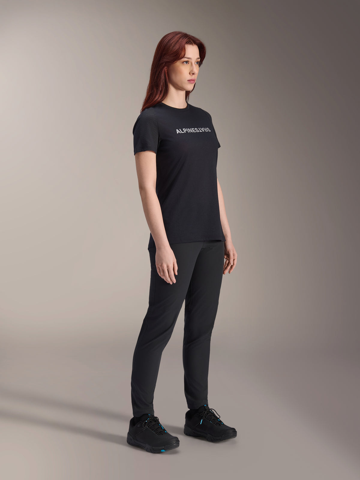 Alpinestars Stella A-Dura Dri Switch Trikot, Kurzarm-Fahrradtrikot, Schwarz mit weißem Alpinestars-Logo, getragen von einem weiblichen Model mit passender schwarzer Hose und Schuhen, vielseitige Ausrüstung für das Mountainbiken.