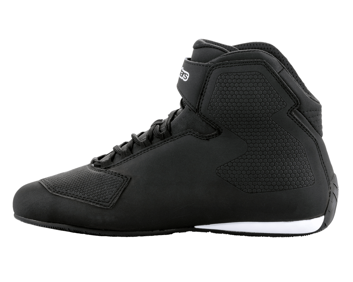 Alpinestars Sektor schoenen, zwart-witte motorschoenen, hoog model, snelvetersysteem met enkelbandje, chassis van getextureerde microvezel, witte zooldetails bij de hiel, slanke beschermende schoenen voor op de weg