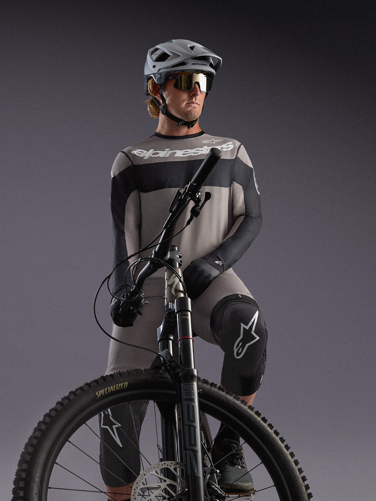 Maillot manches longues Alpinestars A-Dura Race gris, accents noirs, porté par un pilote de VTT équipé.
