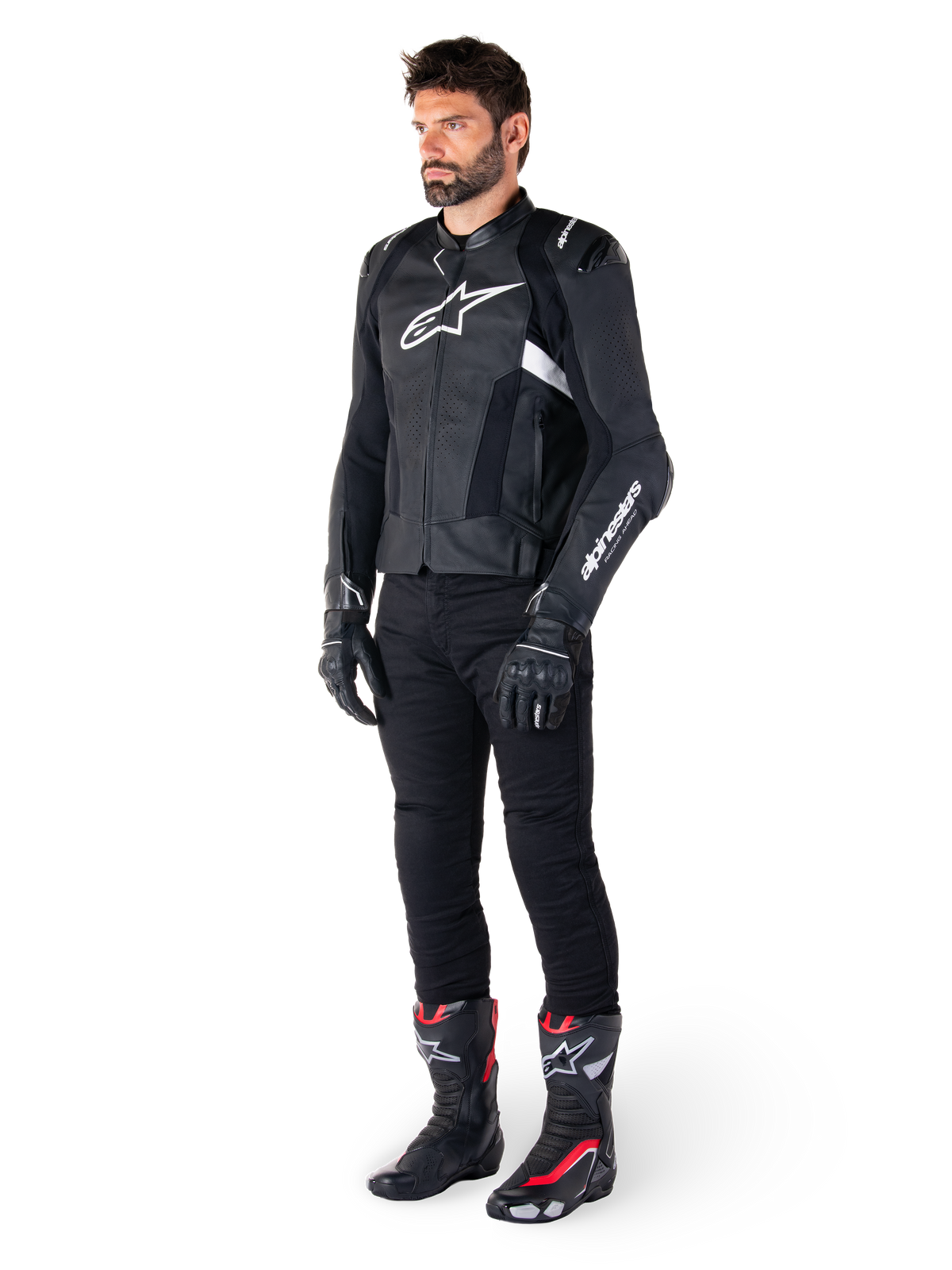 Alpinestars Missile V3 Airflow Lederjacke, Schwarz und Weiß, getragen von einem männlichen Model mit schwarzer Motorradhose, schwarzen Handschuhen und Rennstiefeln mit roten und weißen Akzenten, mit perforiertem Leder und weißem Logo-Branding, Performance-Motorrad-Rennausrüstung