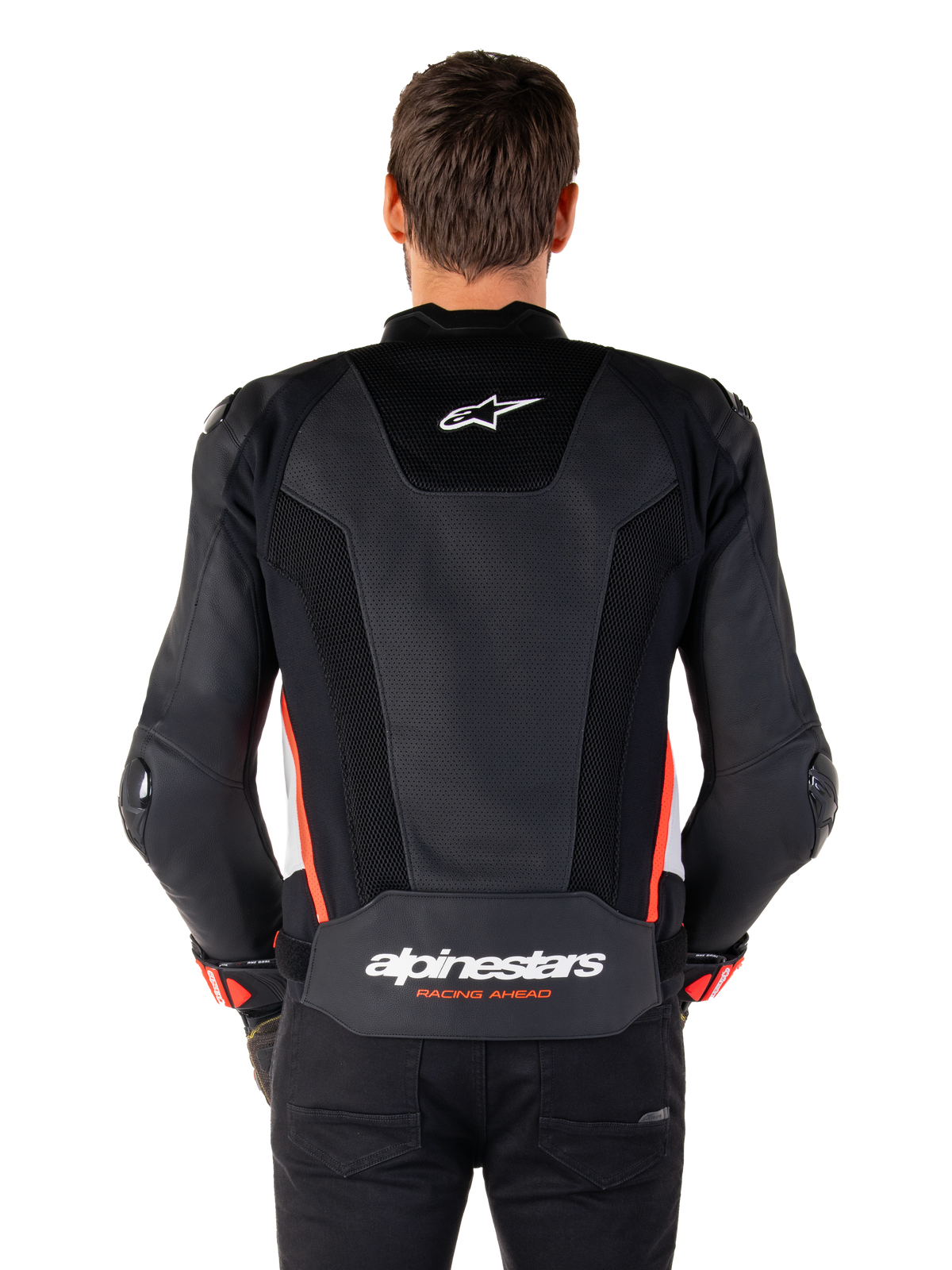 Rückansicht einer Person, die die Alpinestars Missile V3 Airflow Lederjacke in Schwarz Weiß Rot Fluo trägt, mit großflächigen perforierten Lederbahnen zur Belüftung, einem kleinen Alpinestars-Logo auf dem oberen Rücken und dem markanten „alpinestars RACING AHEAD“-Branding am unteren Taillenbereich.