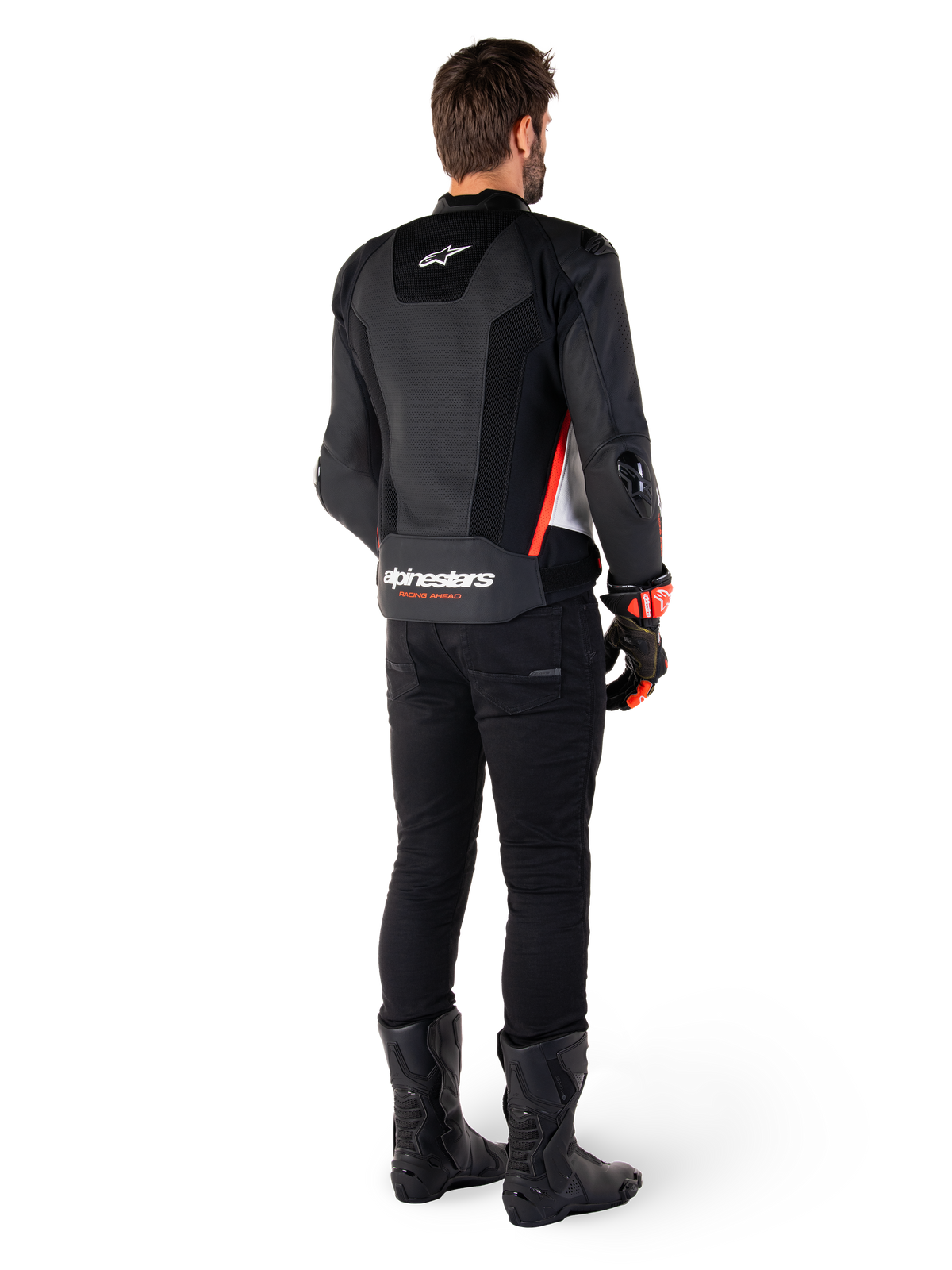 Rückansicht eines Fahrers mit der Alpinestars Missile V3 Airflow Lederjacke in Schwarz Weiß Rot Fluo, kombiniert mit schwarzer Hose und schwarzen Stiefeln, großflächig perforiertes Leder für Belüftung, DFS-Schulterprotektoren und markantes Alpinestars-Branding auf dem unteren Rücken.