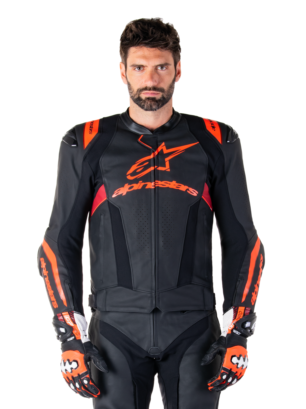 Alpinestars Missile V3 Ignition leren motorjas, racejas, zwart en rood fluo, gedragen met bijpassende racehandschoenen en leren broek, voorzien van geperforeerde ventilatie en opvallende Alpinestars branding, professionele race-uitrusting