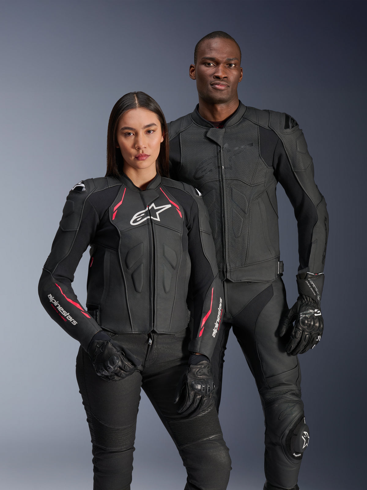 Vestes en cuir Alpinestars Dusk Airflow et Stella Dusk, motards homme et femme portant des vestes de moto en cuir noir, veste homme dotée de cuir perforé pour la ventilation, veste femme avec accents rouges et logos blancs, coordonnés avec un pantalon et des gants de moto noirs, équipement de sport moto haute performance