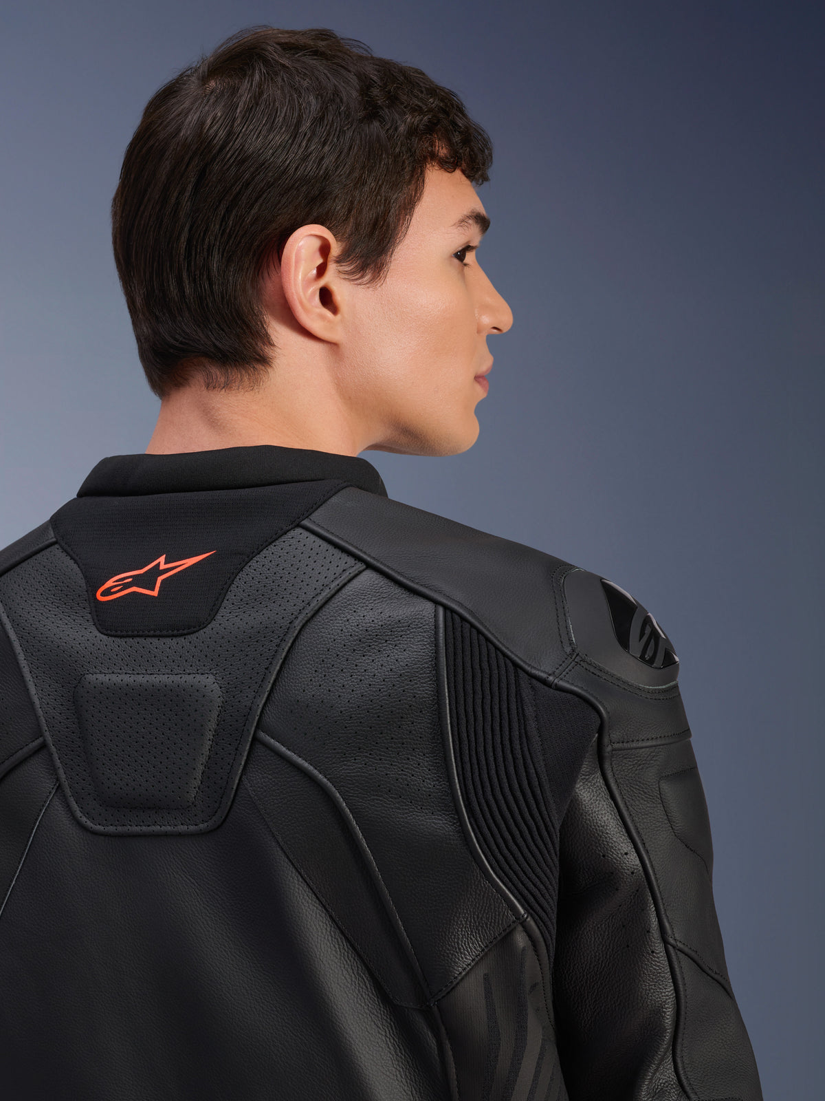 Alpinestars GP Plus R V4 Airflow Leather Jacket, Black, close-up rear view on a model, featuring perforated race-grade leather, technical stretch panels, and a small orange Alpinestars logo on the collar, professional motorcycle riding apparel