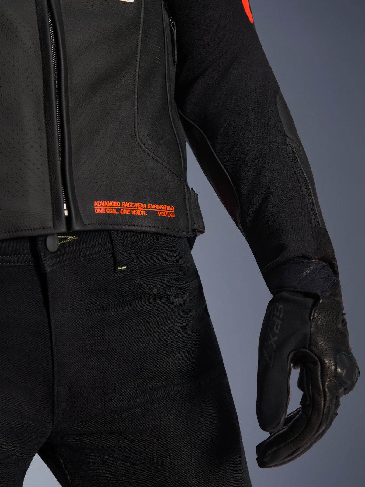 Veste en cuir Alpinestars GP Plus R V4 Airflow, gros plan sur la taille et la manche, cuir noir perforé avec marquage rouge fluo « Advanced Racewear Engineering », associée à un pantalon de moto noir et un gant de moto SPX 7