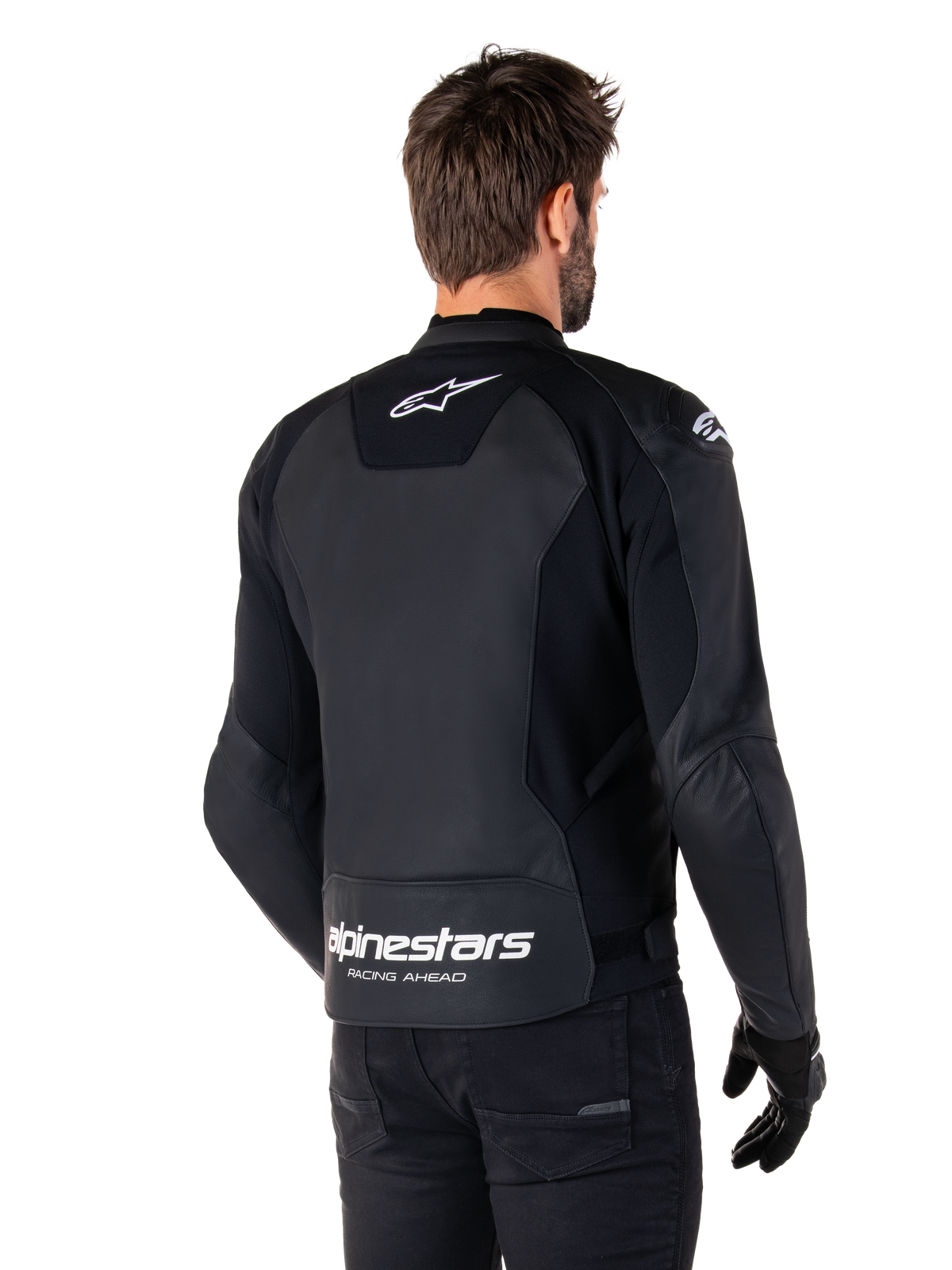 Alpinestars Faster V3 Lederjacke, Schwarz und Weiß, Rückansicht an einem Fahrer, mit weißem Stern-Logo auf dem oberen Rücken und großem Alpinestars-Branding mit „Racing Ahead“ am unteren Abschluss, verlängerte Rückseite für bessere Abdeckung beim Fahren, hochwertige Sport-Lederkonstruktion