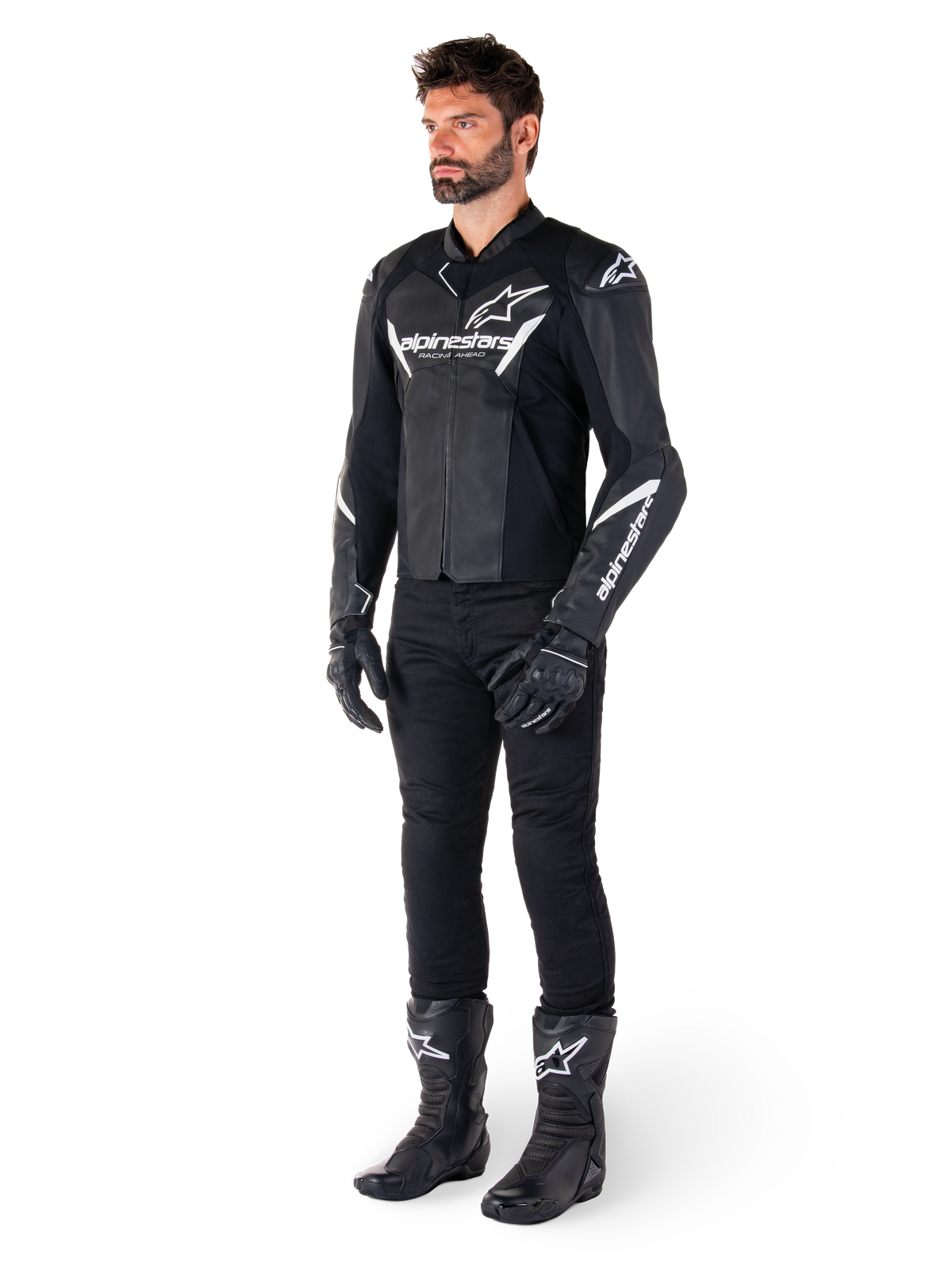 Männliches Modell in Alpinestars Faster V3 Lederjacke, Sport-Motorradjacke, Schwarz und Weiß, kombiniert mit schwarzer Motorradhose, Handschuhen und Stiefeln, mit weißen Brandings und Logos, sportliche Silhouette für den Straßenrennsport