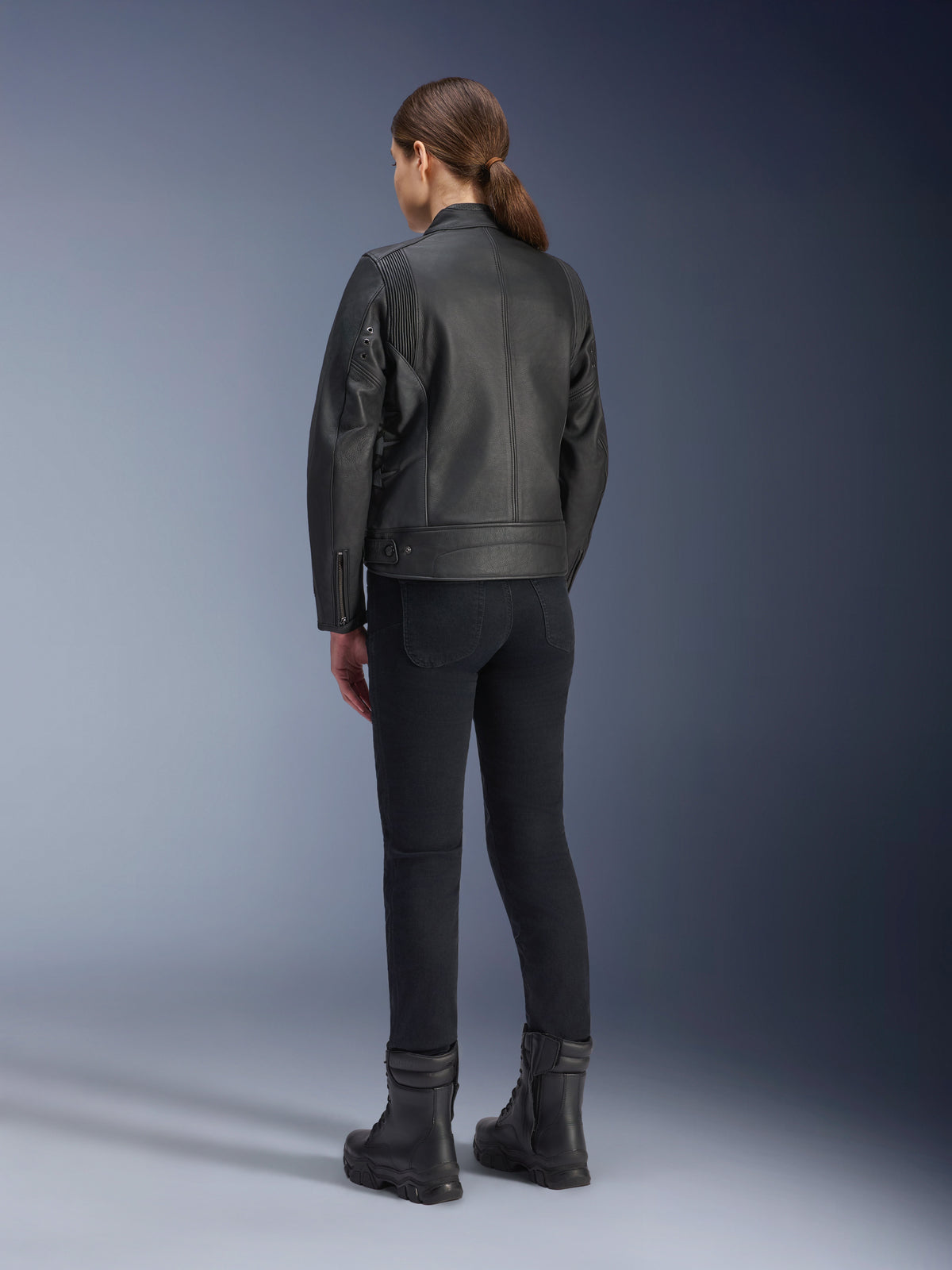 Alpinestars Stella Dyno Leren Jas, dames motorjas, zwart, achteraanzicht met hoogwaardige leren constructie en getailleerde pasvorm, gedragen met zwarte motorbroek en zwarte laarzen, urban rijstijl