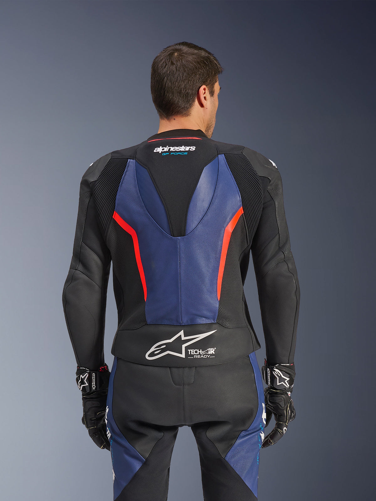 Alpinestars GP Force V2 Lederkombi 2-teilig, Rückansicht, Schwarz mit blauen und rot-fluoreszierenden Akzenten, perforierte Lederkonstruktion, Tech-Air Ready-Branding an der Taille, ergonomische Stretch-Panels für Rennsport-Performance.