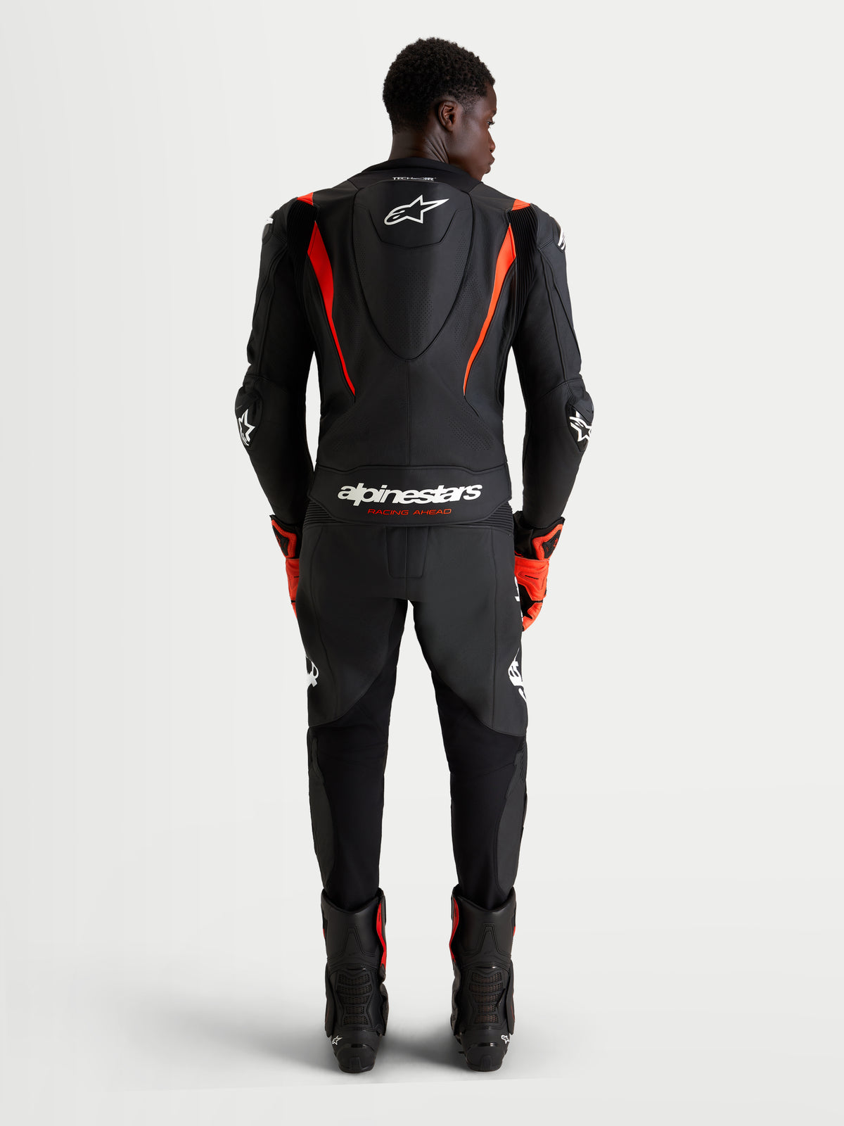 Alpinestars Missile V3 2-delig leren pak, motorracingpak voor heren, zwart en rood fluo, aerodynamische bult en CE-gecertificeerde bescherming, achteraanzicht van rijder in racekleding