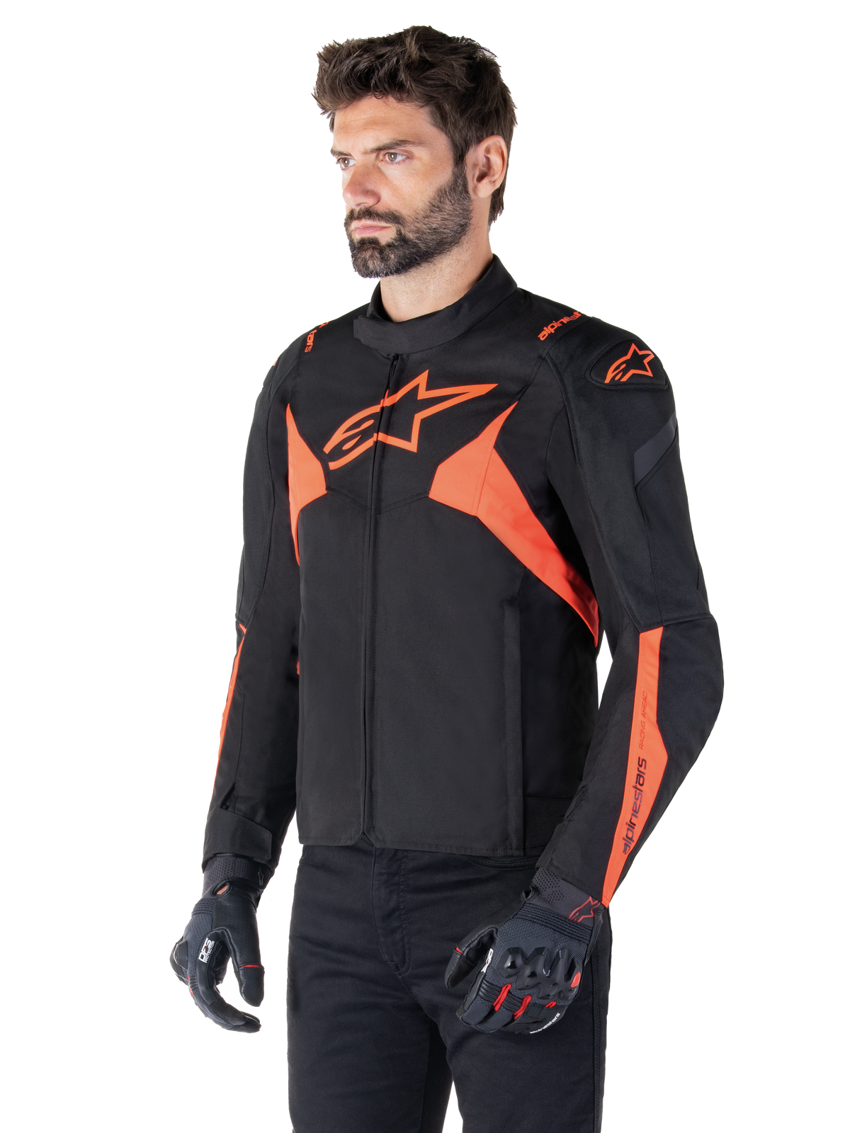 Veste imperméable Alpinestars T-Jaws V4, Noir et Rouge Fluo, veste de moto sport portée par un mannequin homme, arborant des logos d'étoiles orange sur la poitrine et les épaules, associée à des gants et un pantalon noirs